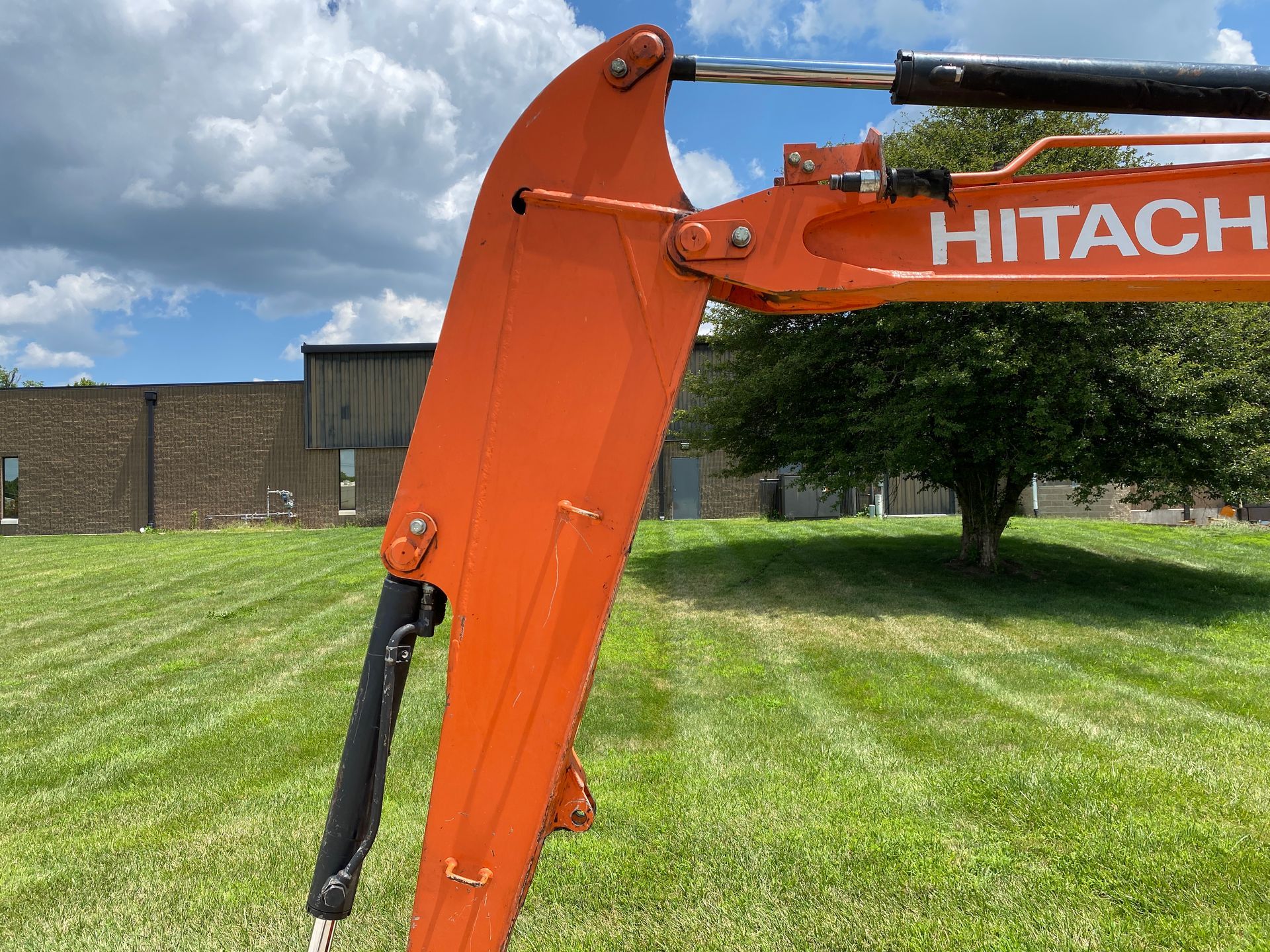 Close-up of a track from an orange mini excavator on a concrete sidewalk.