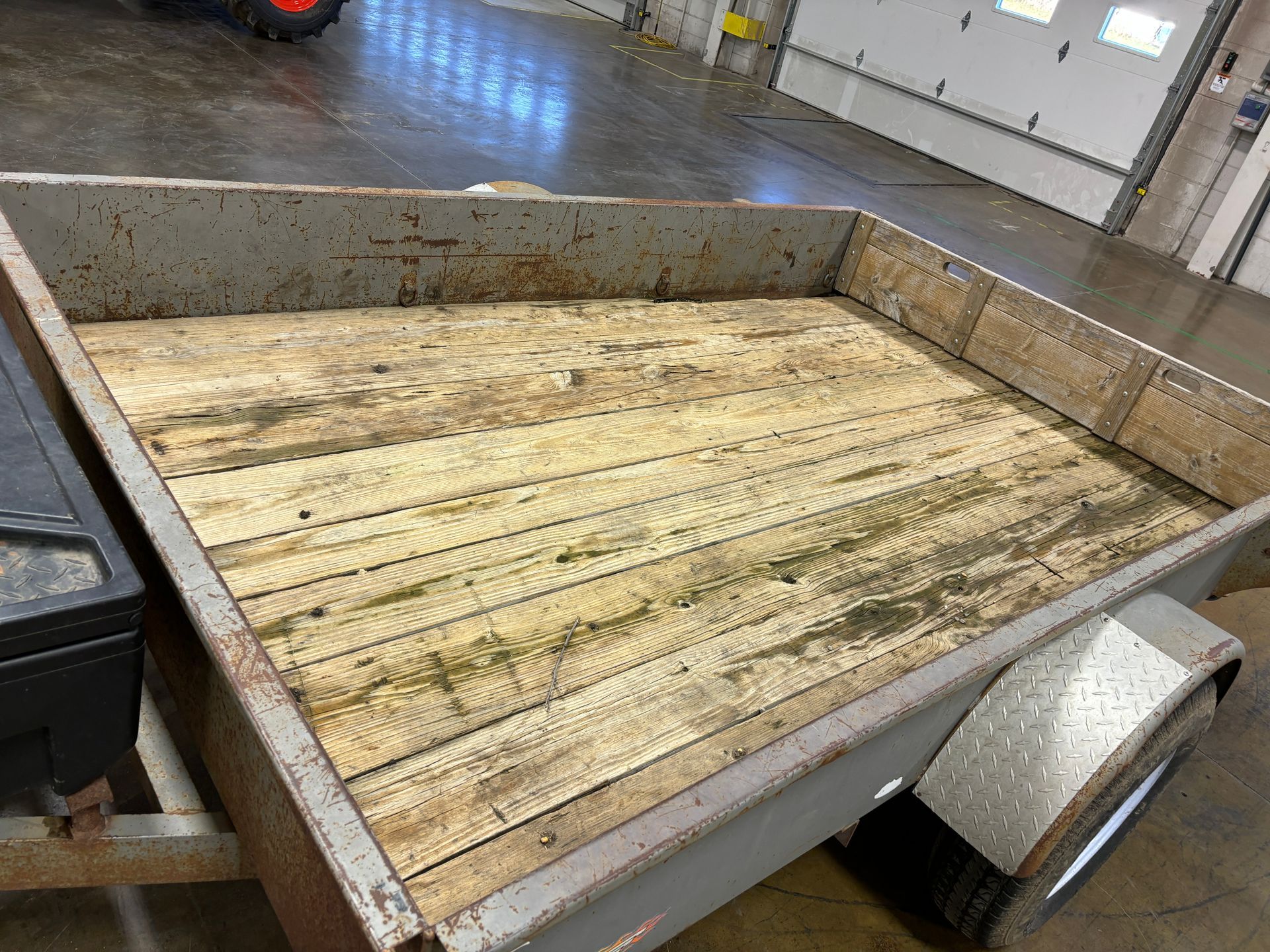Trailer with weathered wooden bed and metal sides, parked inside a building.