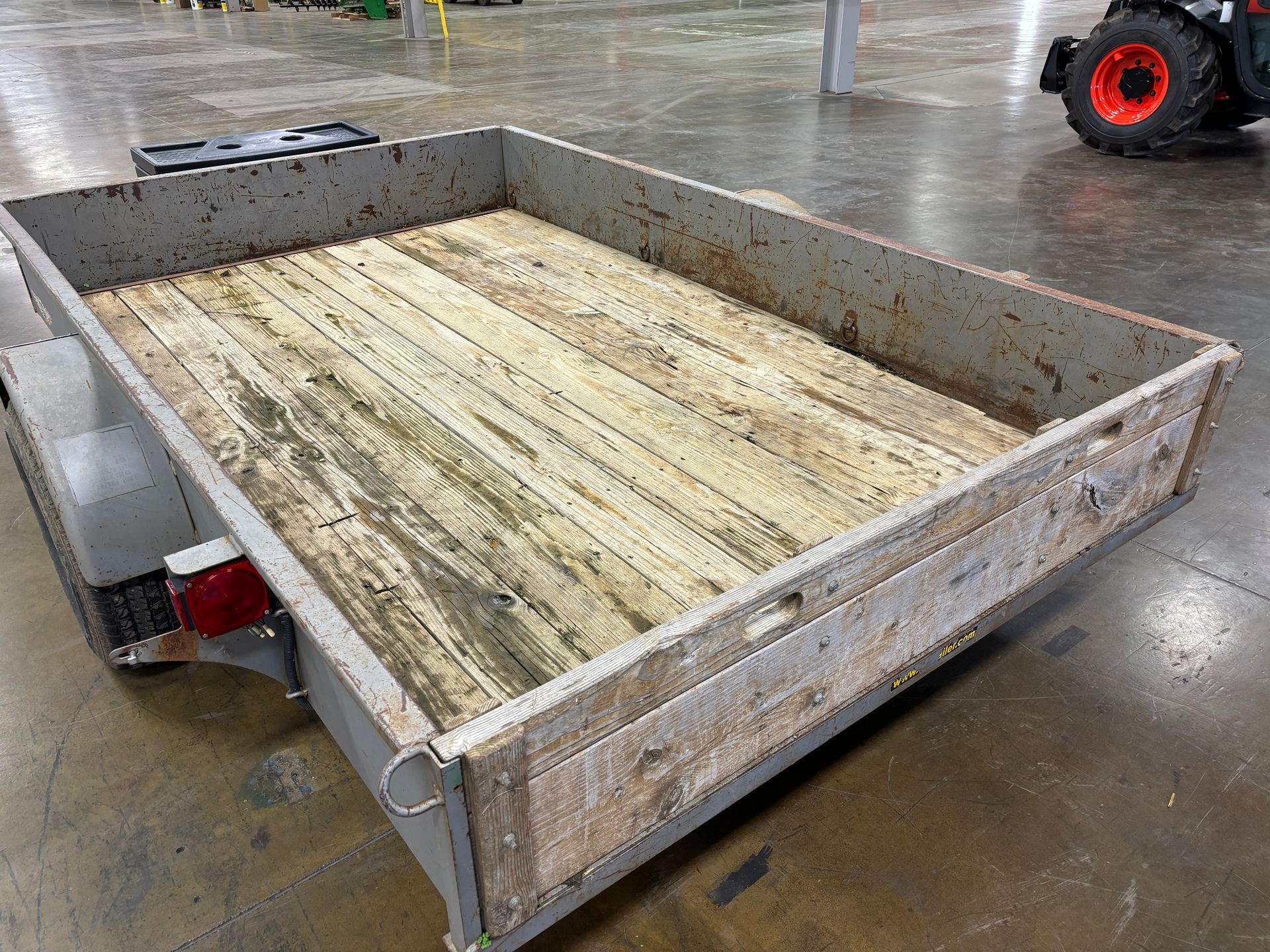 Utility trailer with a wooden floor in a warehouse setting.