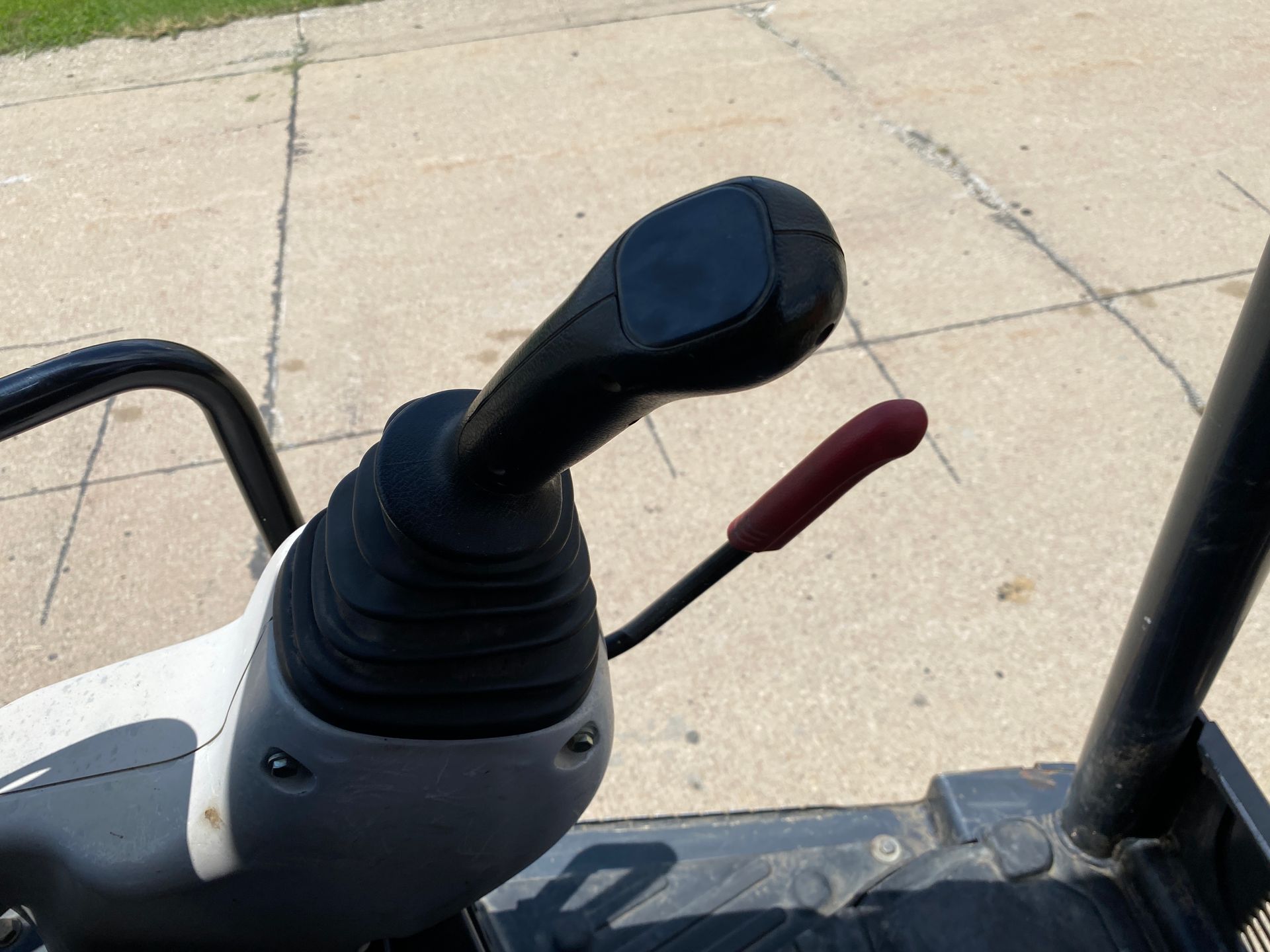 Black and white joystick controls of a construction machine. Red lever present.