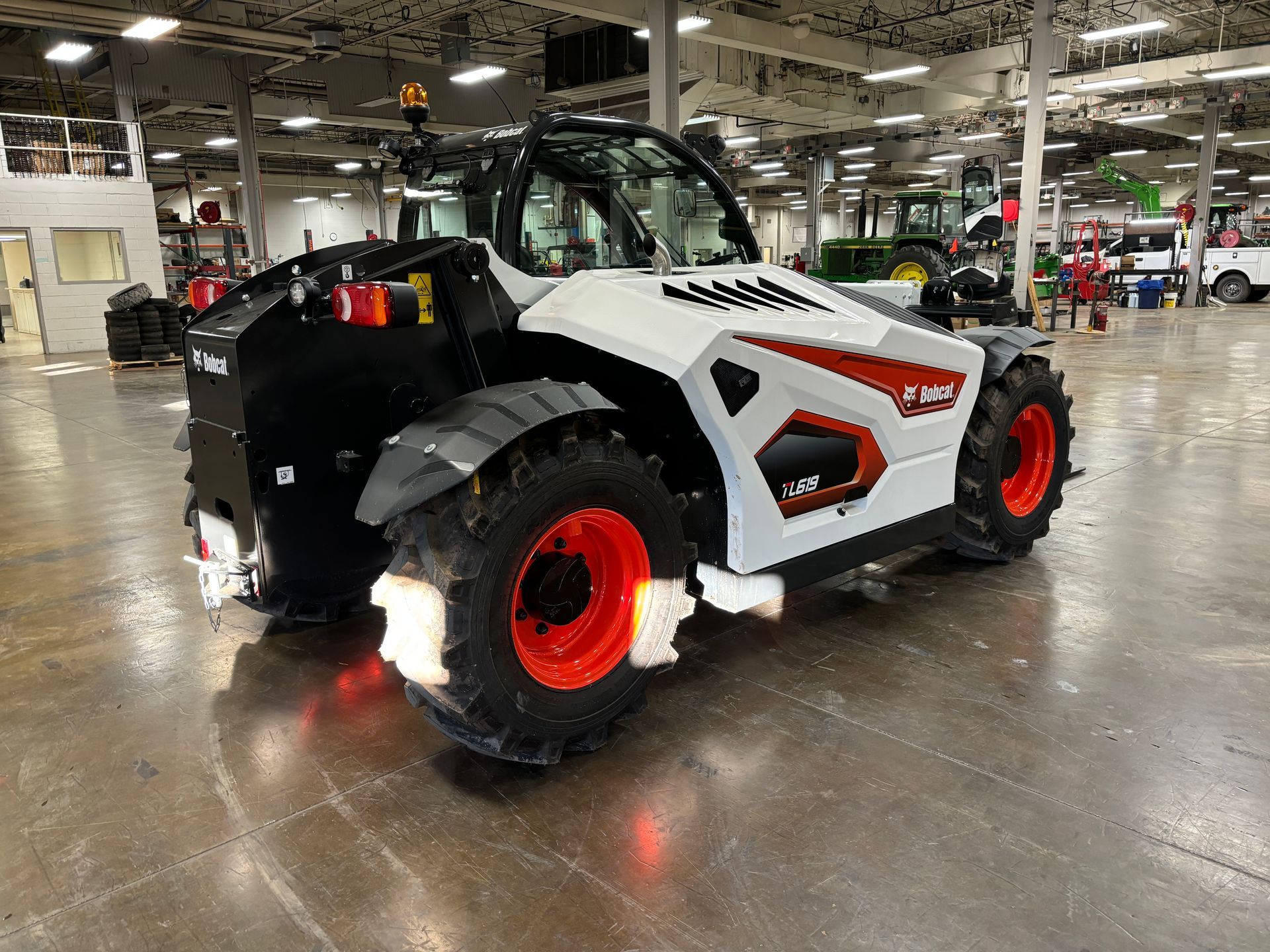 White Bobcat telehandler with red accents parked inside a warehouse.