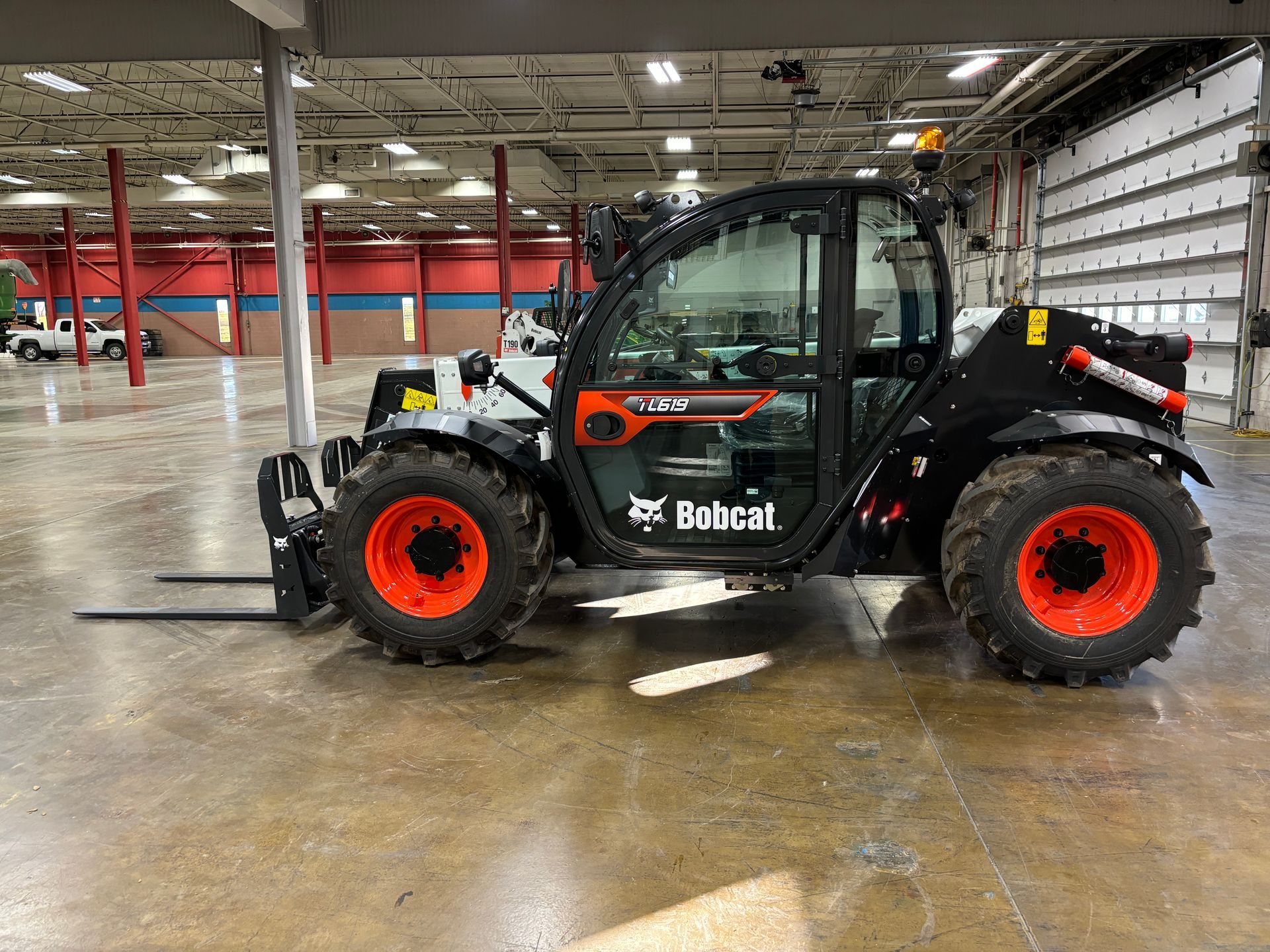 Bobcat telehandler with orange wheels inside a large building.