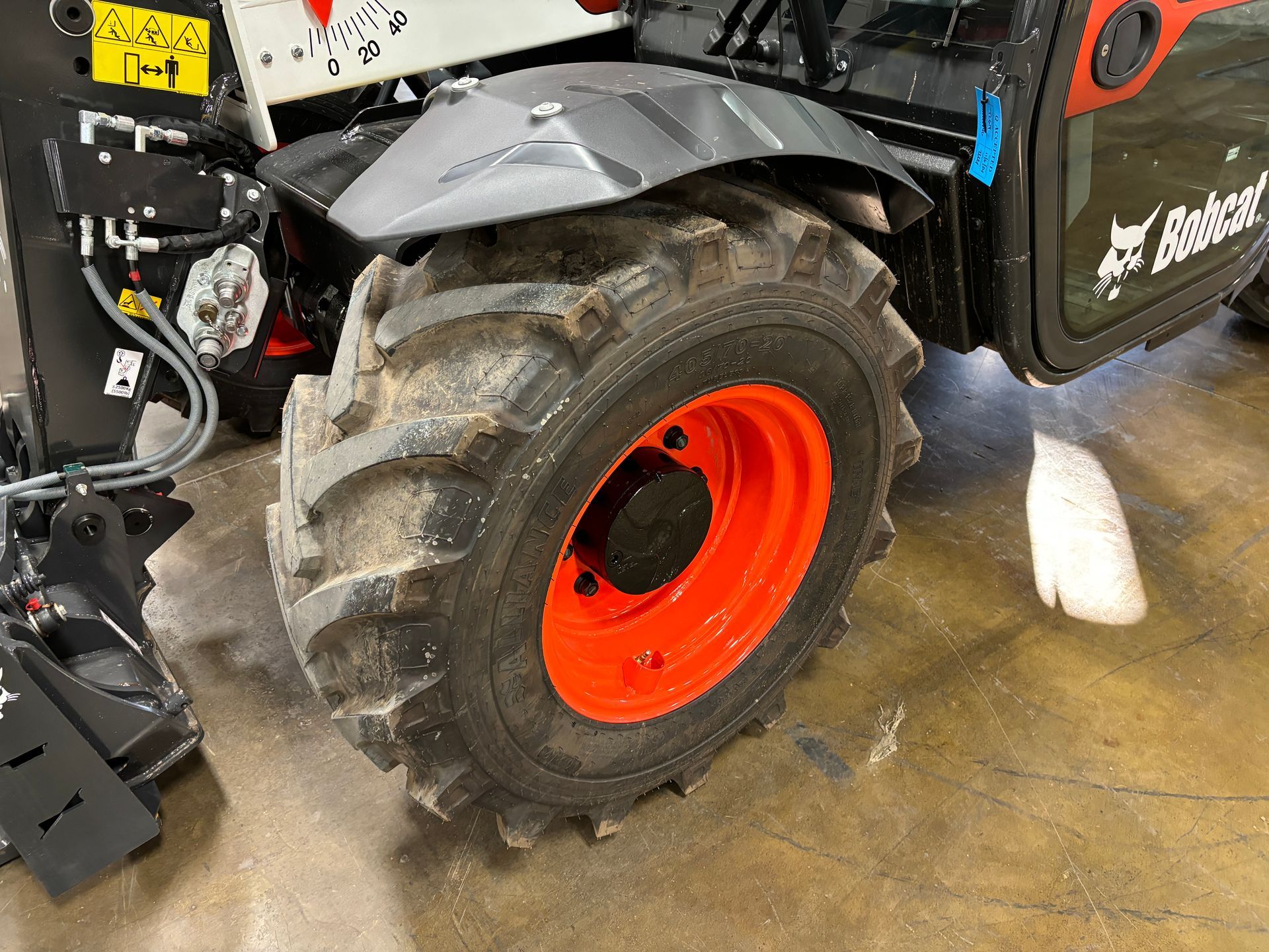 Close-up of a Bobcat wheel. The tire is black and chunky, and the rim is orange.