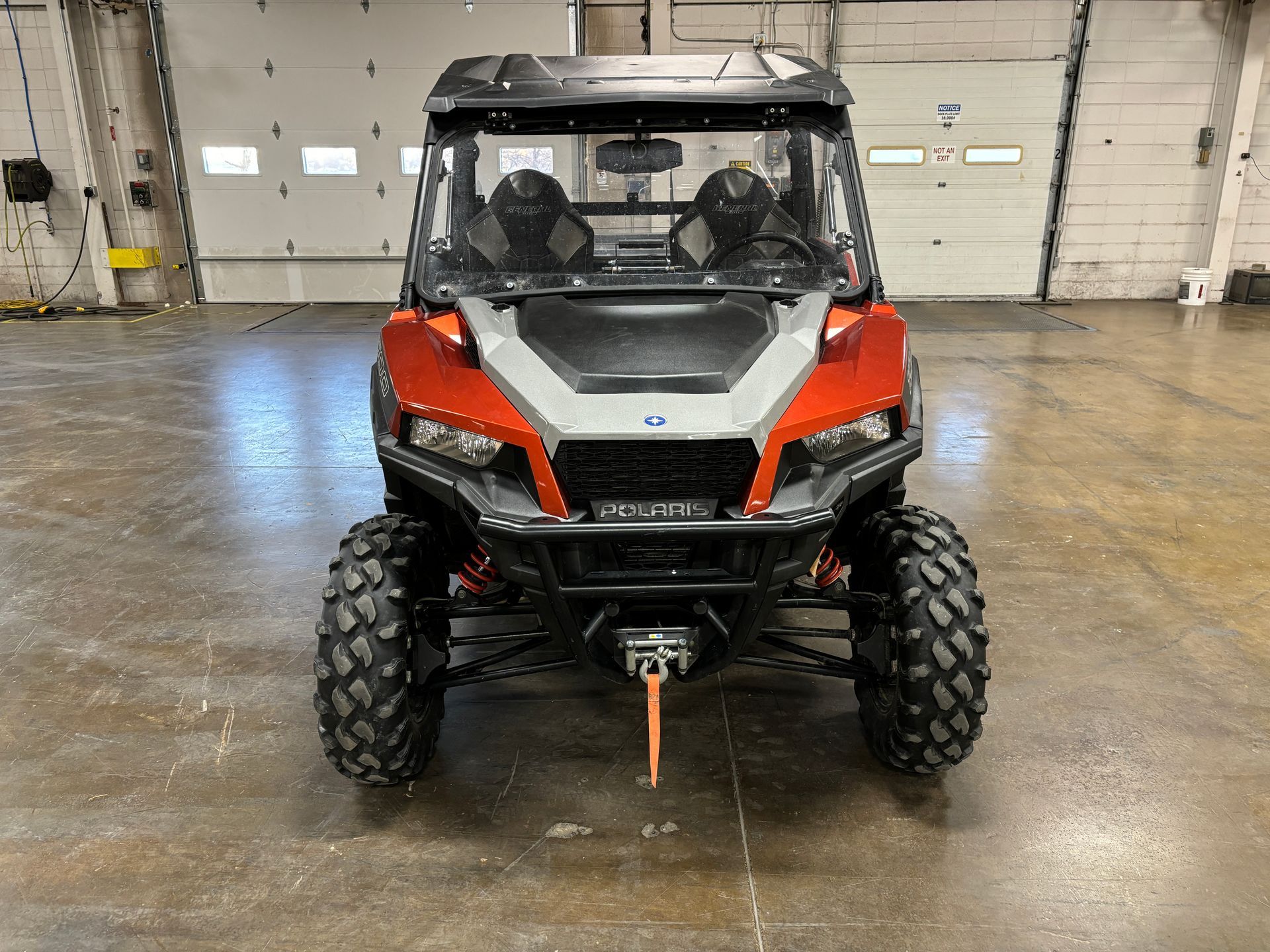 Red and gray Polaris General UTV with a black roof, parked inside a garage.