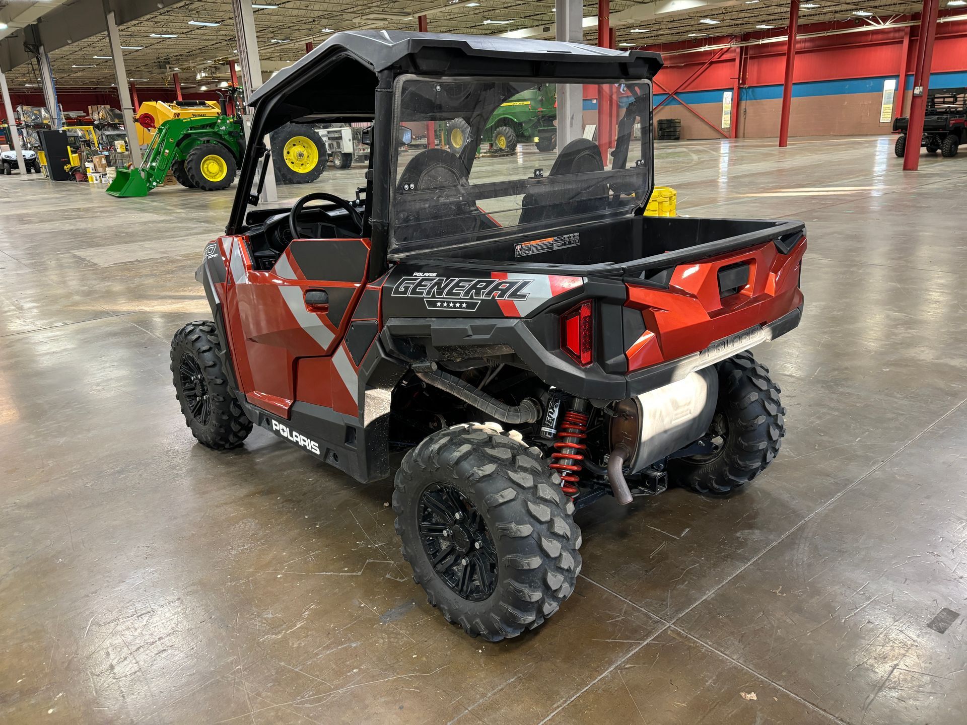 Red and black Polaris General side-by-side utility vehicle in a warehouse.