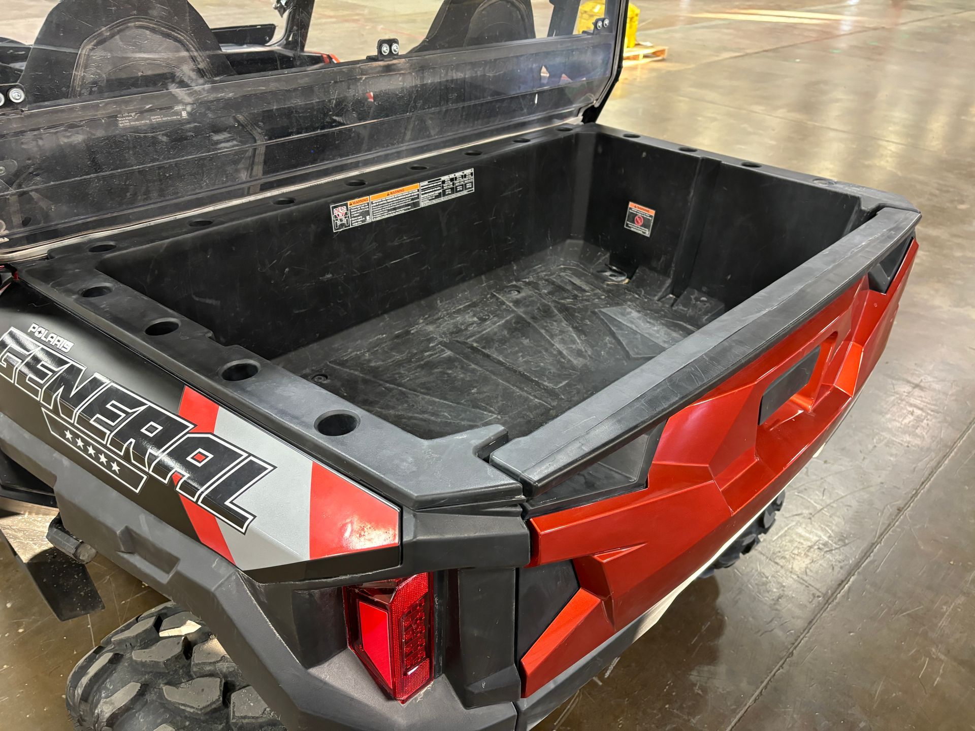 Open black cargo bed on a red and black side-by-side vehicle.