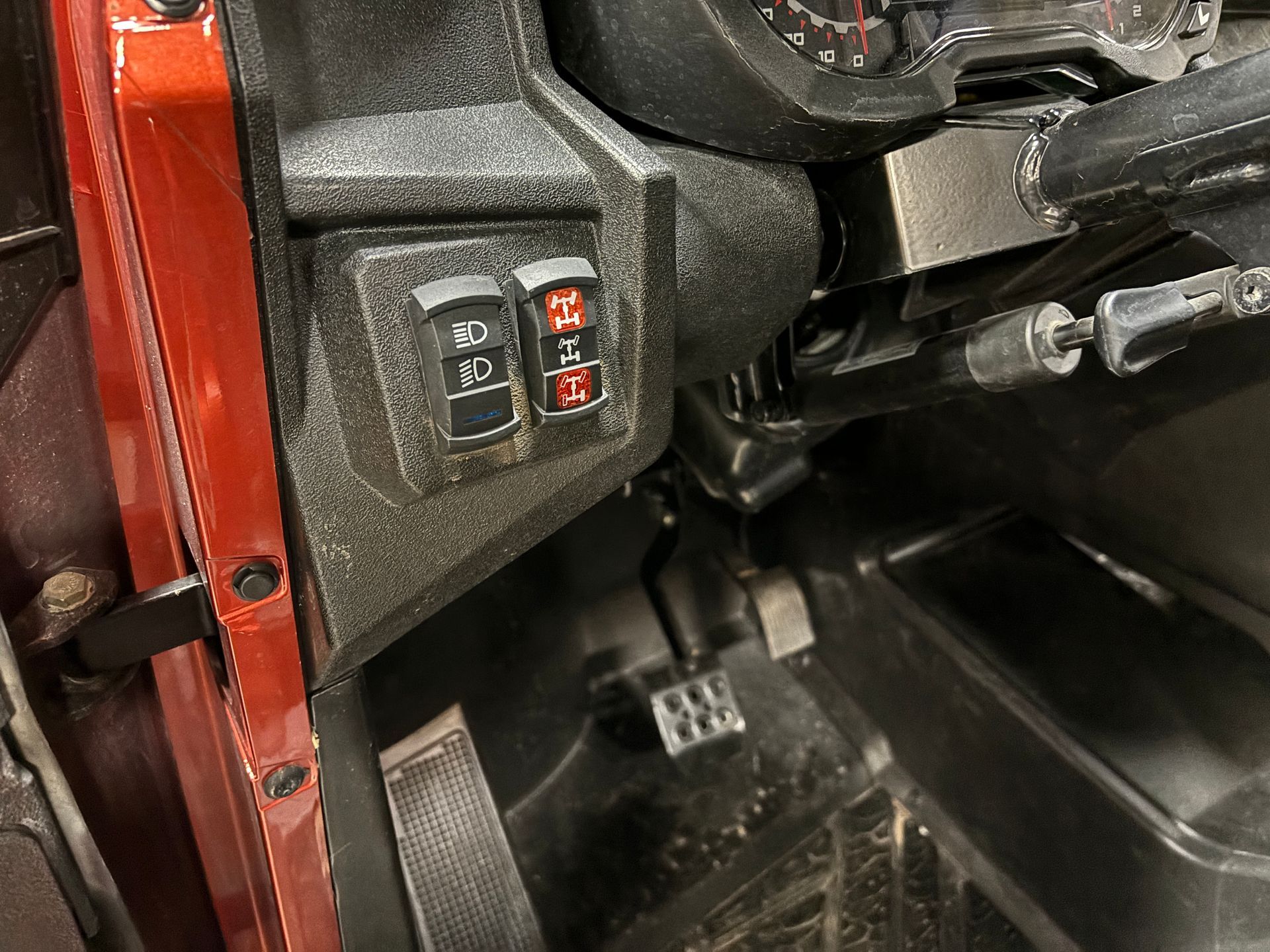 Dashboard detail of a red off-road vehicle with light and 4WD switch controls.