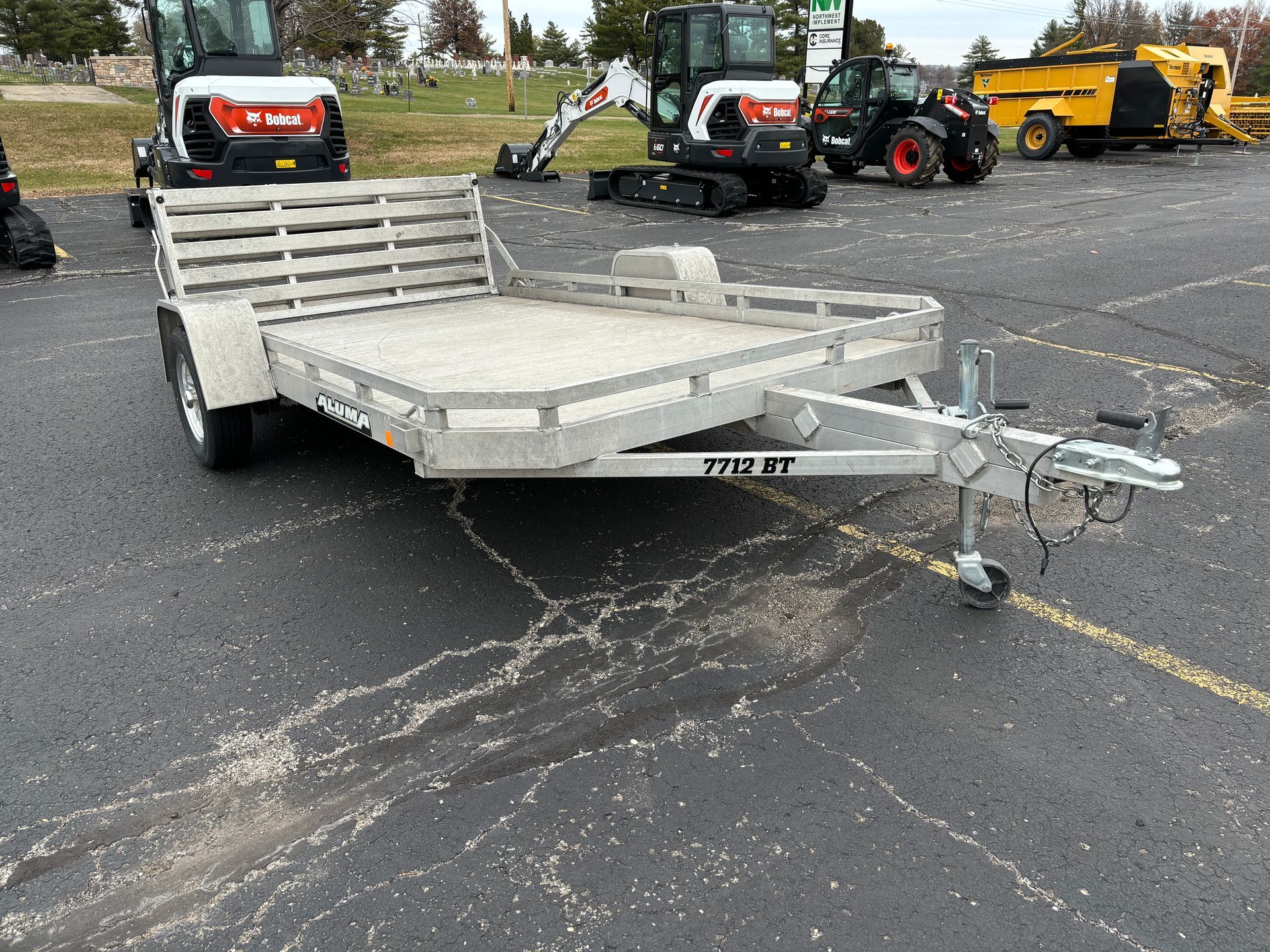 Aluminum utility trailer on asphalt in a parking lot.