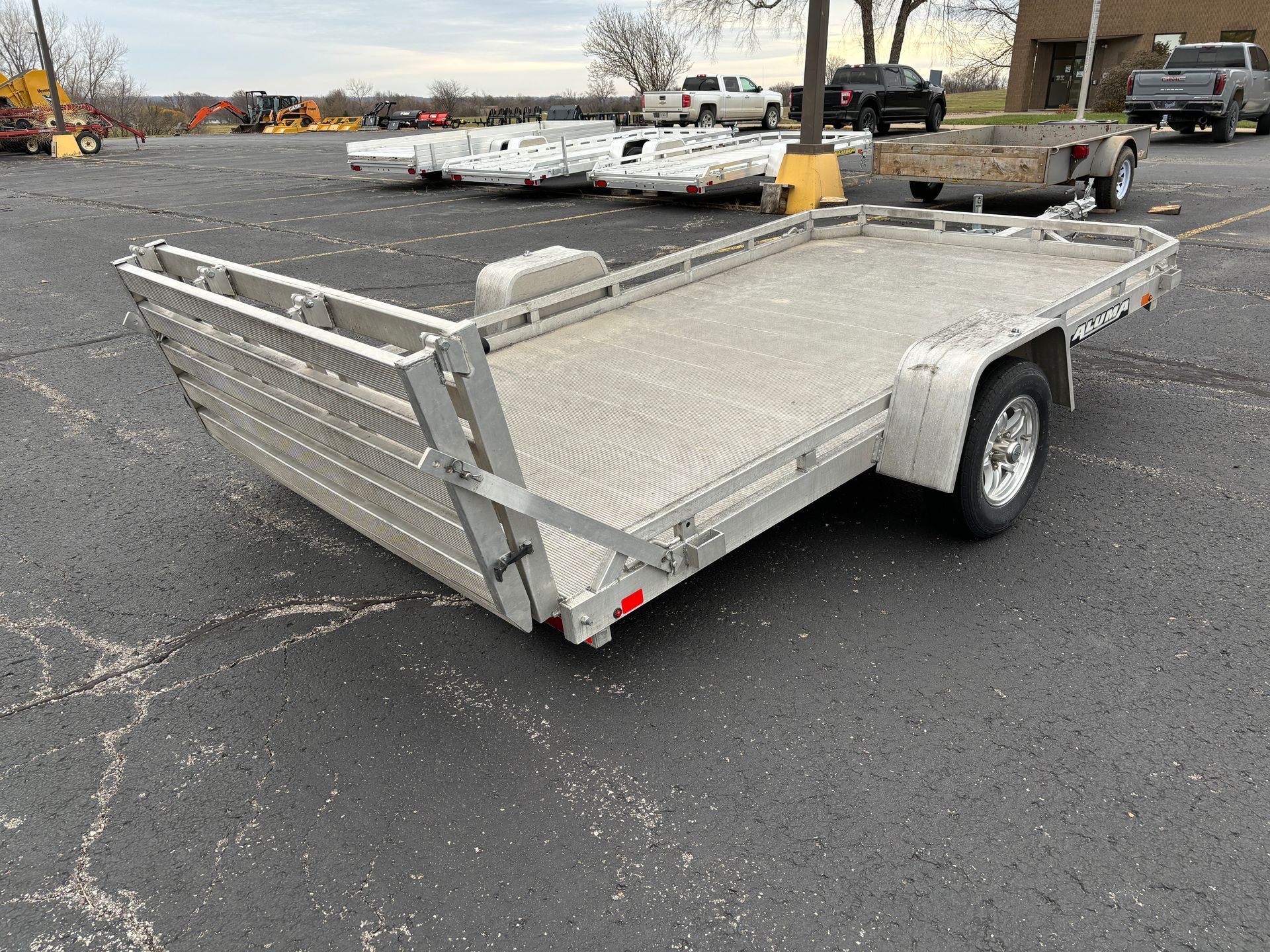 Aluminum flatbed trailer parked on asphalt lot.