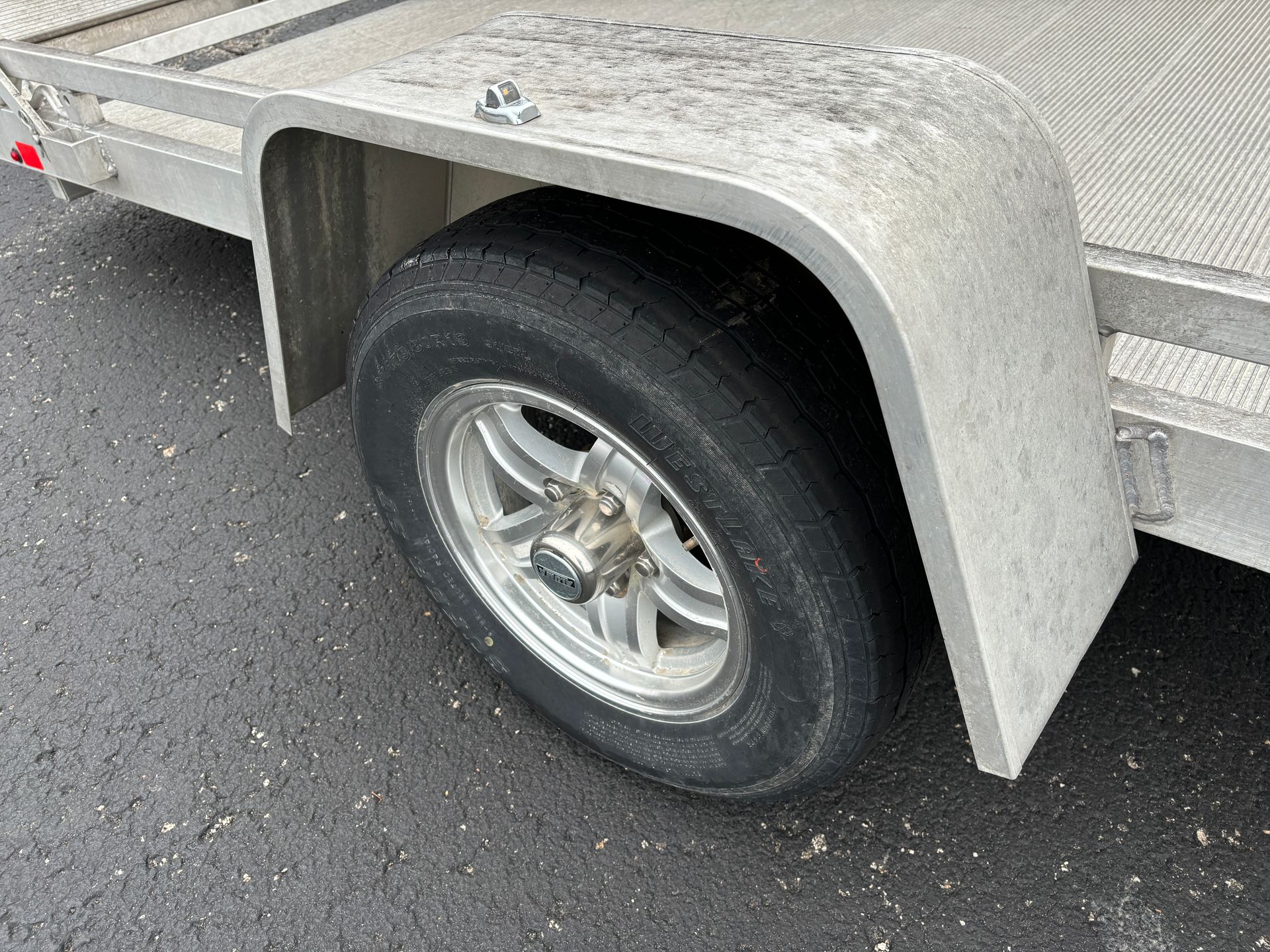 Trailer wheel and fender. Aluminum trailer bed, black tire, gray fender.