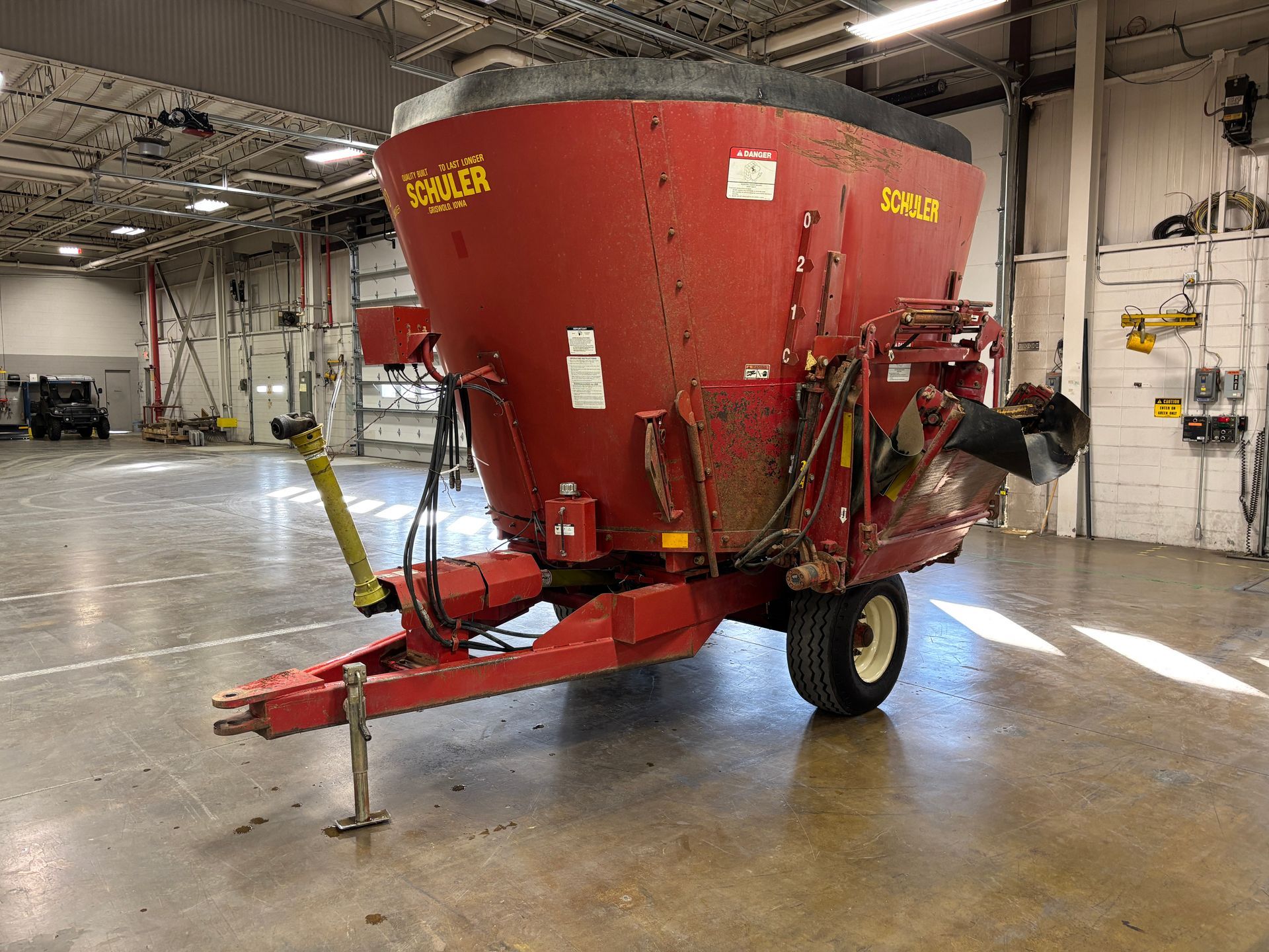 Red mixer wagon with SCHULER branding, parked inside a warehouse, front angled shot.