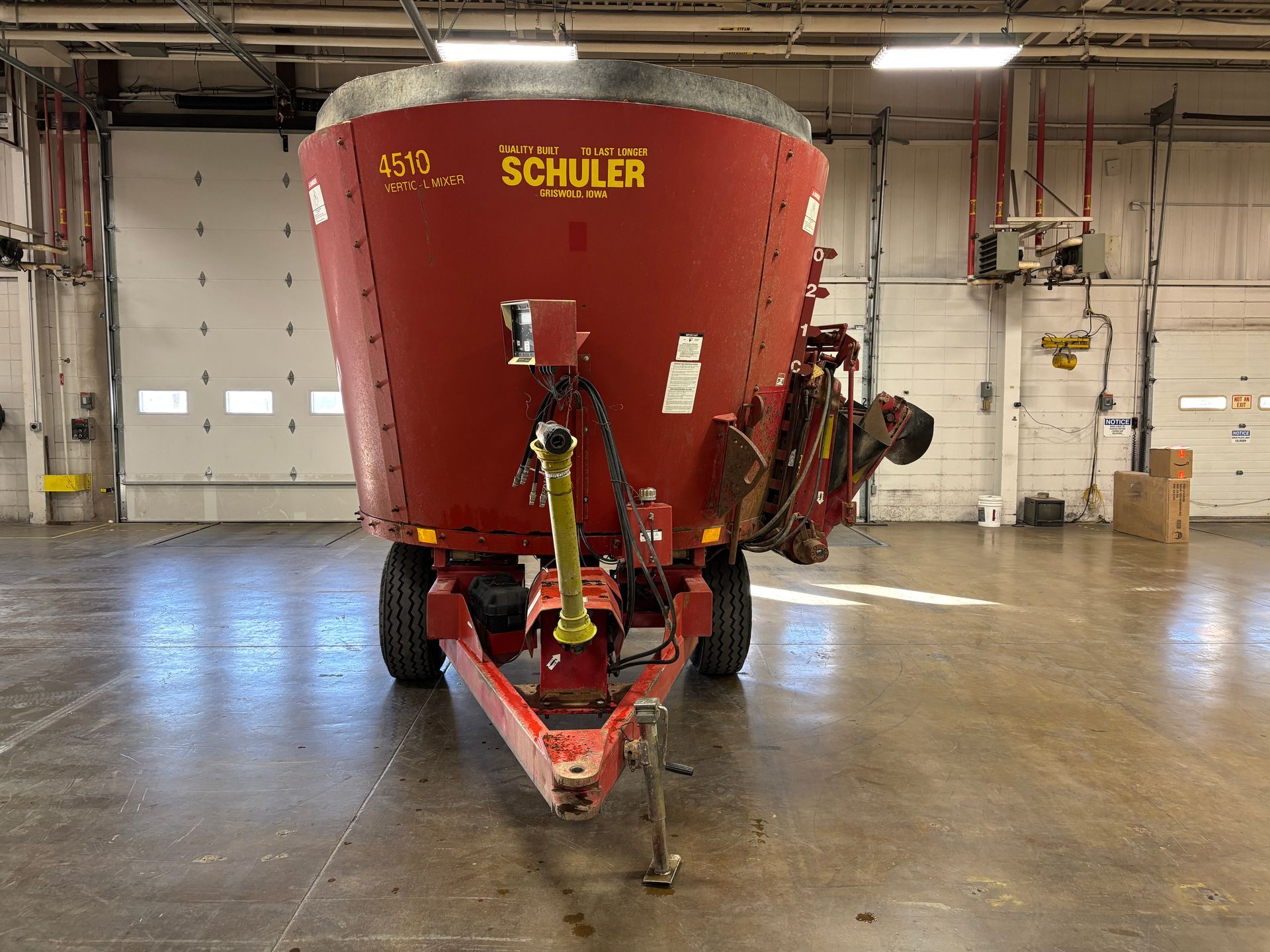 Red mixer wagon with SCHULER branding, parked inside a warehouse, front shot.