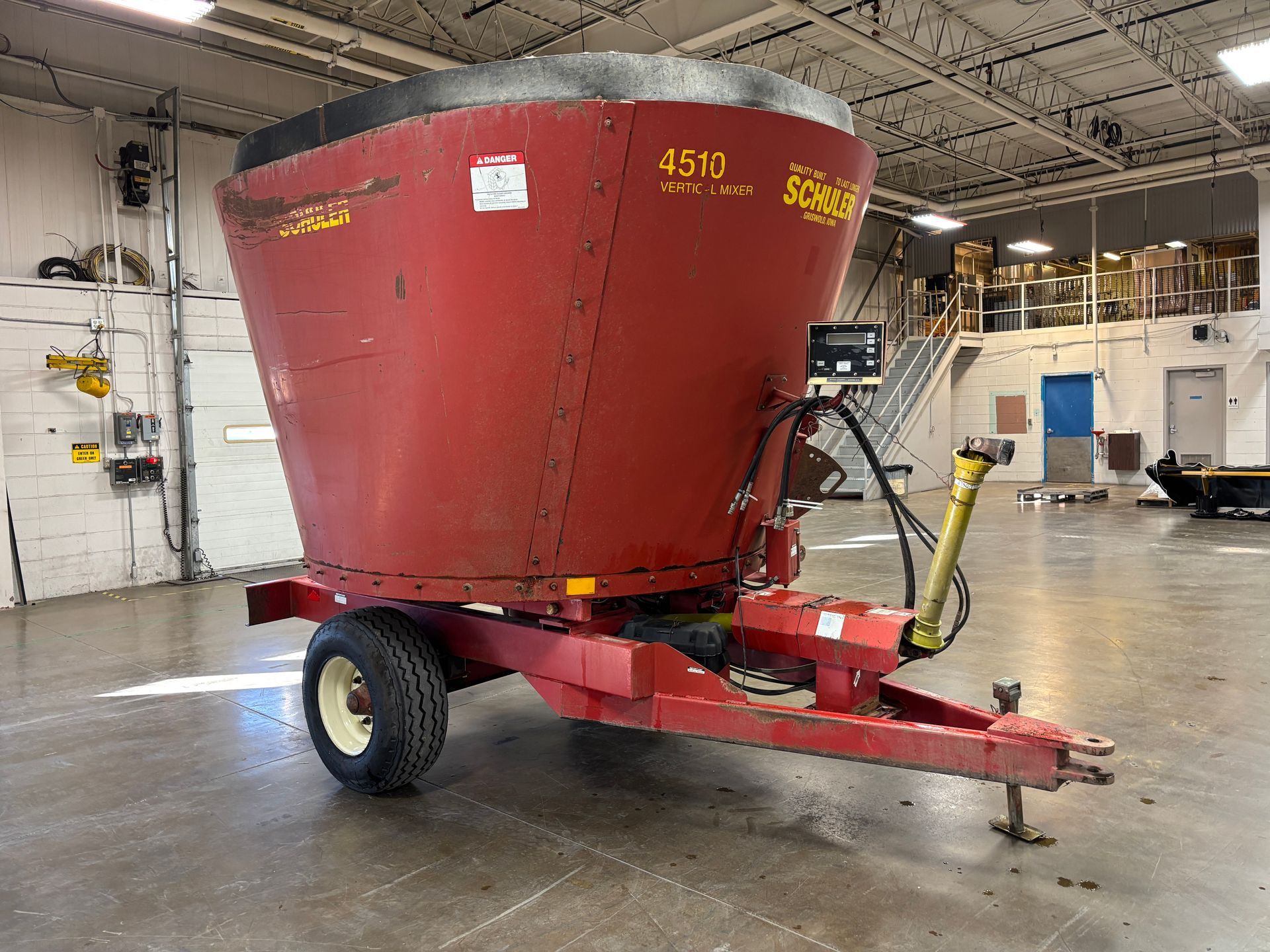 Red mixer wagon with SCHULER branding, parked inside a warehouse, front angled shot.