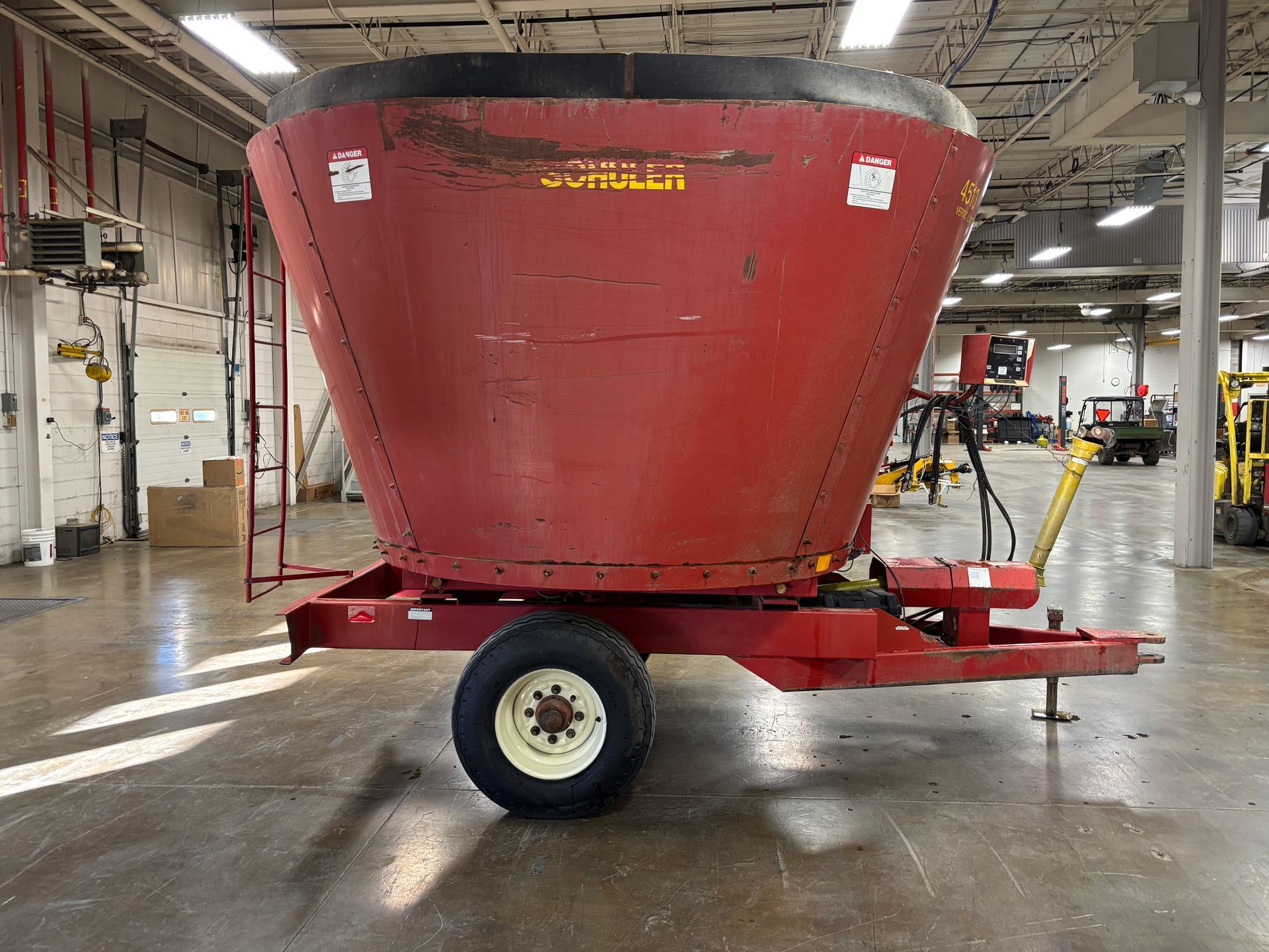 Red mixer wagon with SCHULER branding, parked inside a warehouse, side view shot.