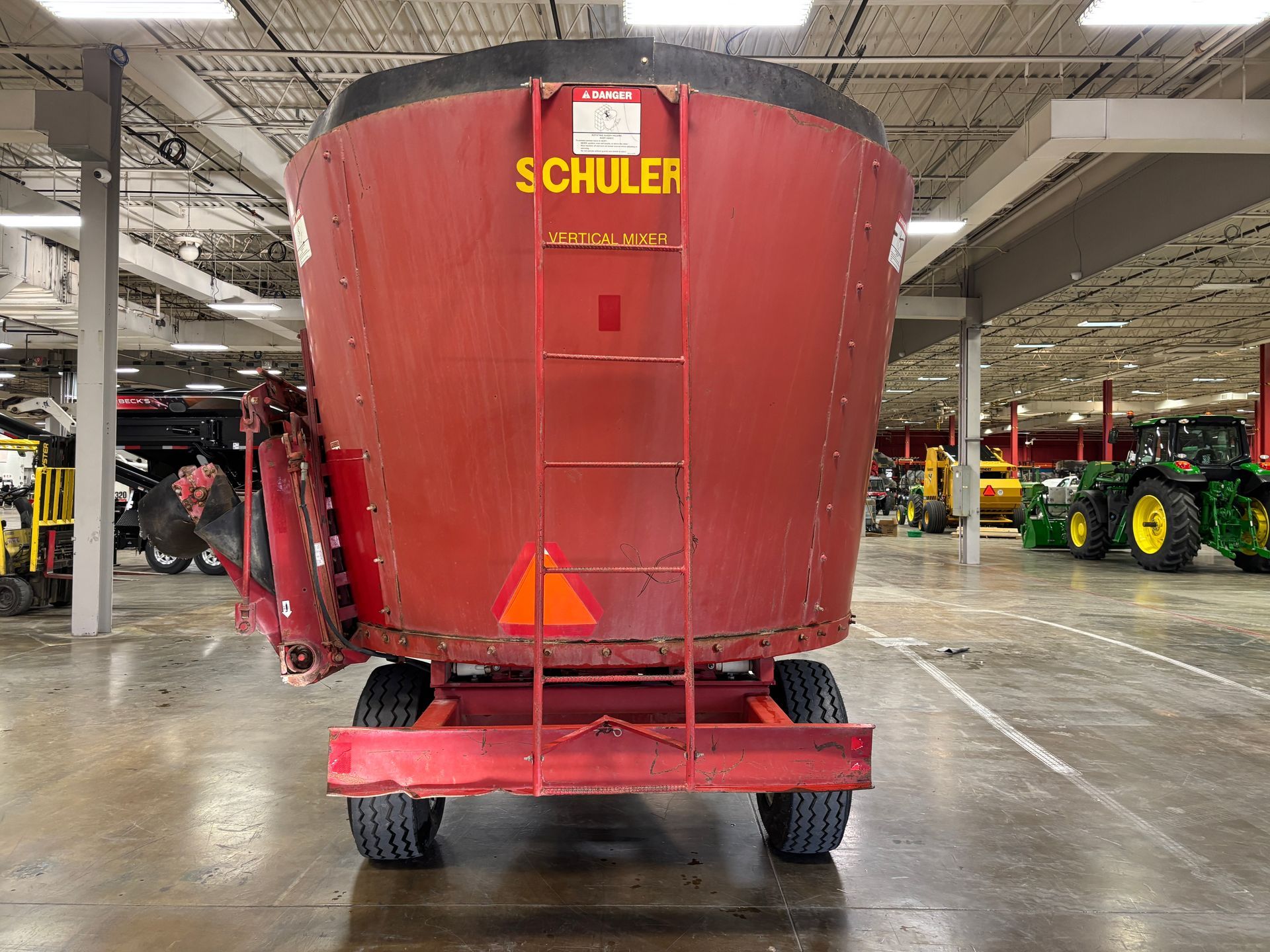 Red mixer wagon with SCHULER branding, parked inside a warehouse, back shot.