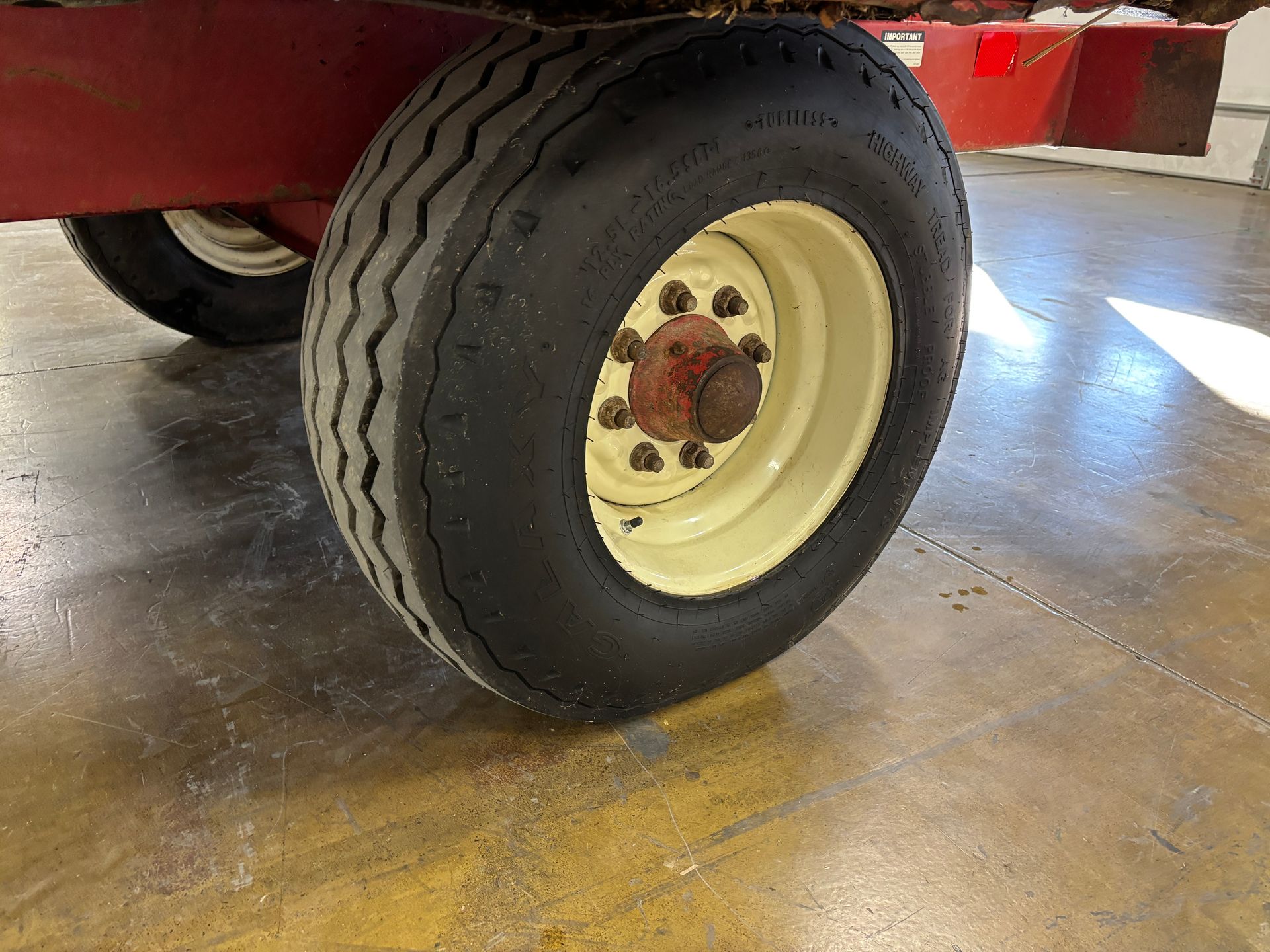 Close-up of a wagon wheel with a black tire on a red wagon.