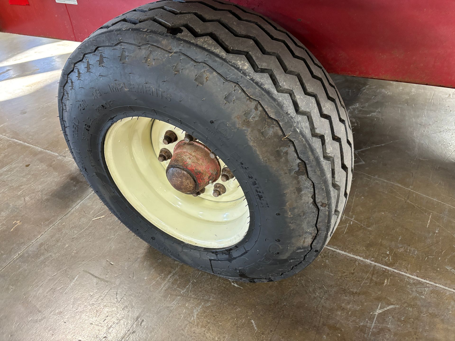 Close-up of a wagon wheel with a black tire on a red wagon.