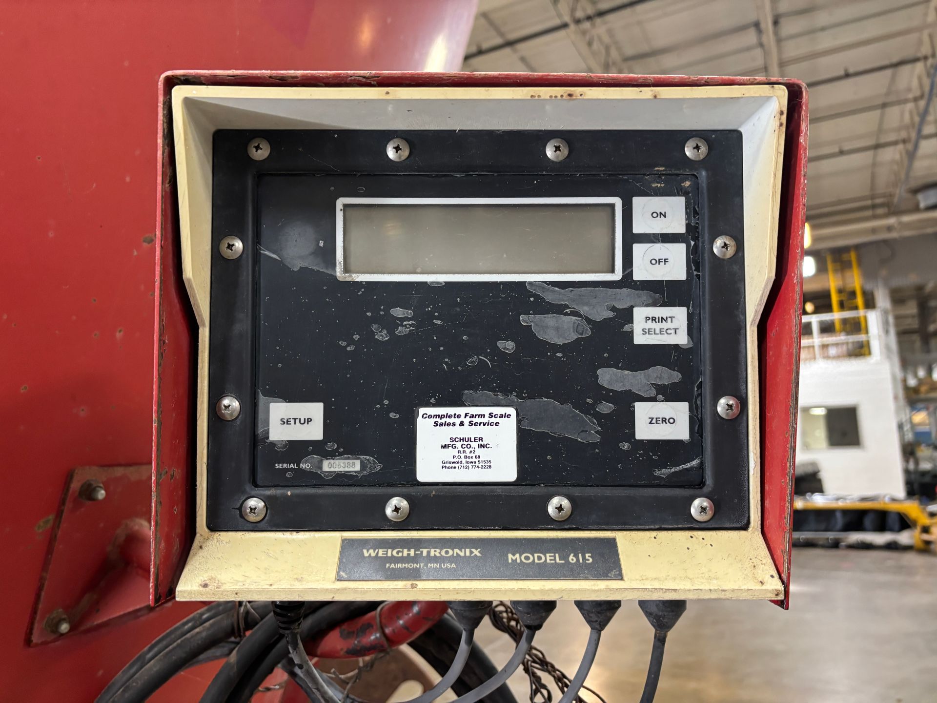 Control panel on a red mixer wagon. Black display with buttons, enclosed in a white and red frame.