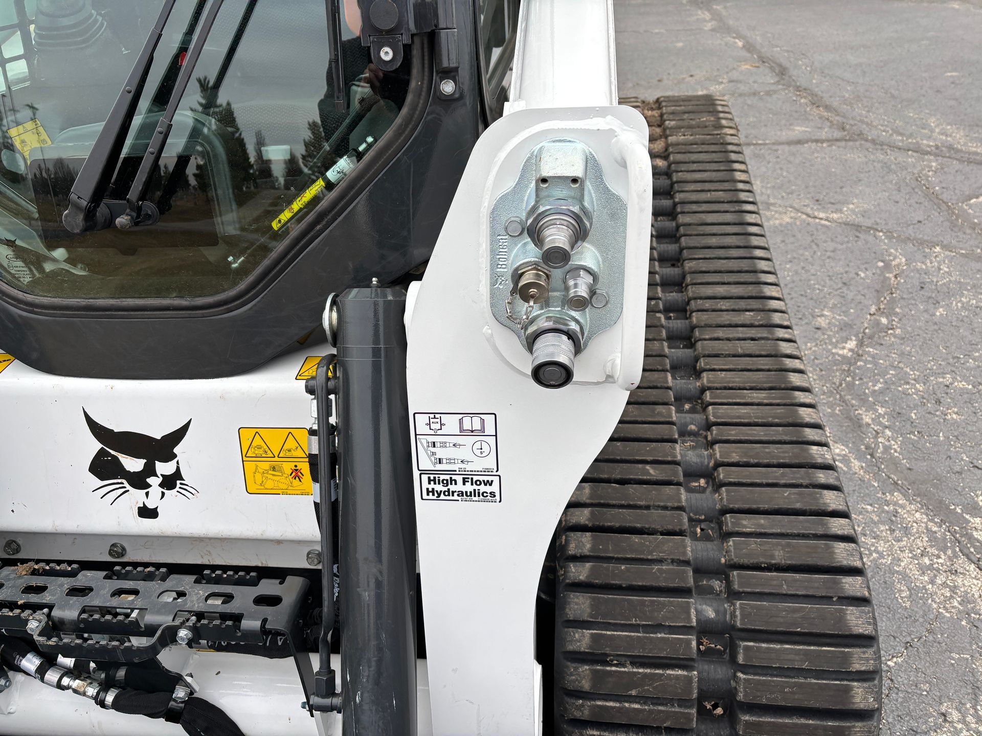 White Bobcat compact track loader, showing hydraulic quick couplers and track.