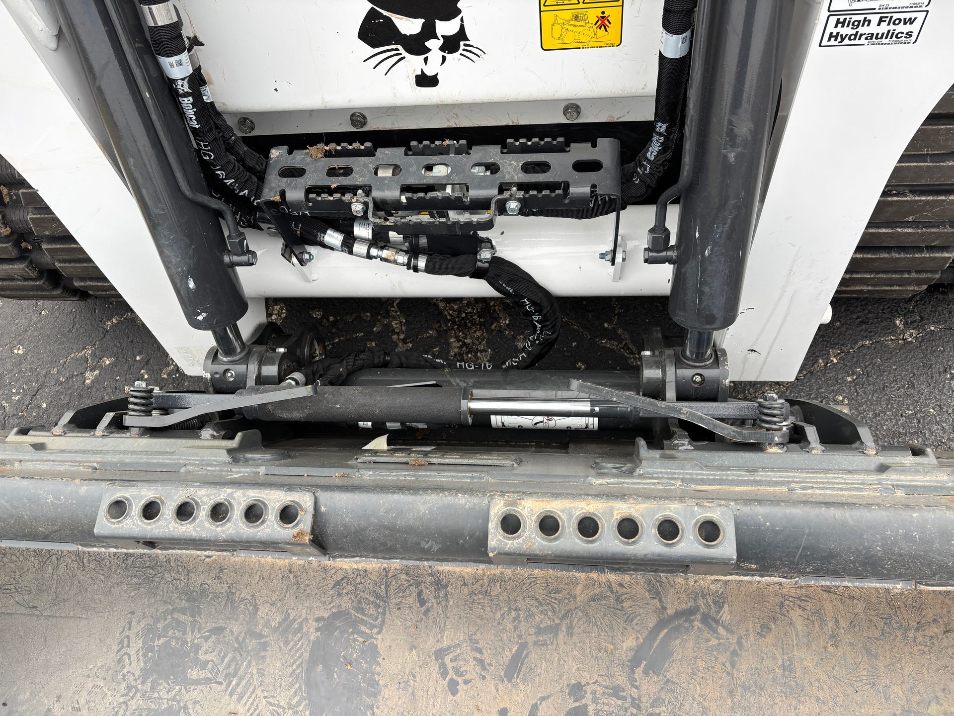 White Bobcat compact track loader bucket and lift arms. Black hydraulics, metal bucket edge with holes.