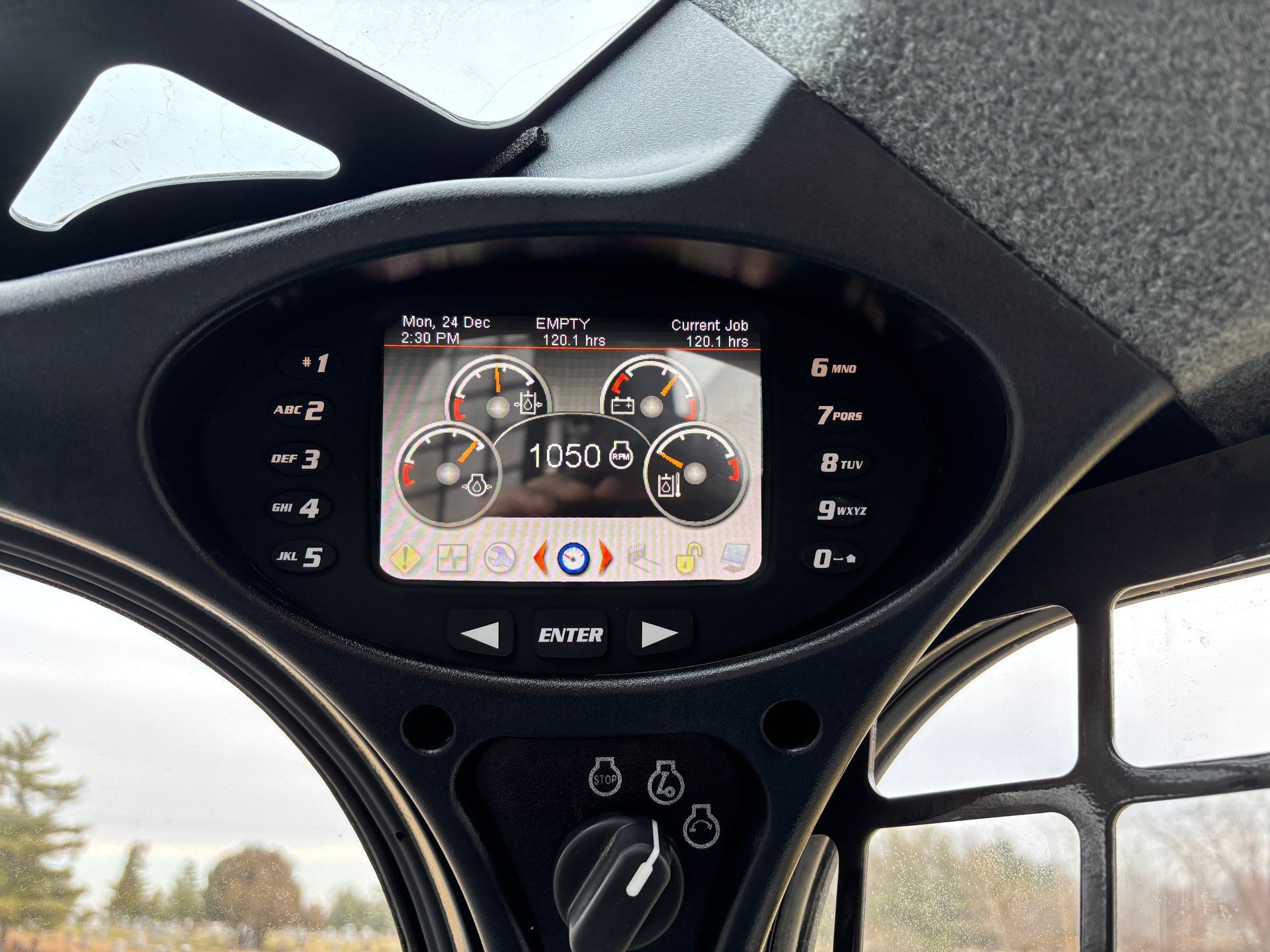 Dashboard display with gauges, engine hours, and control buttons in a compact track loader.