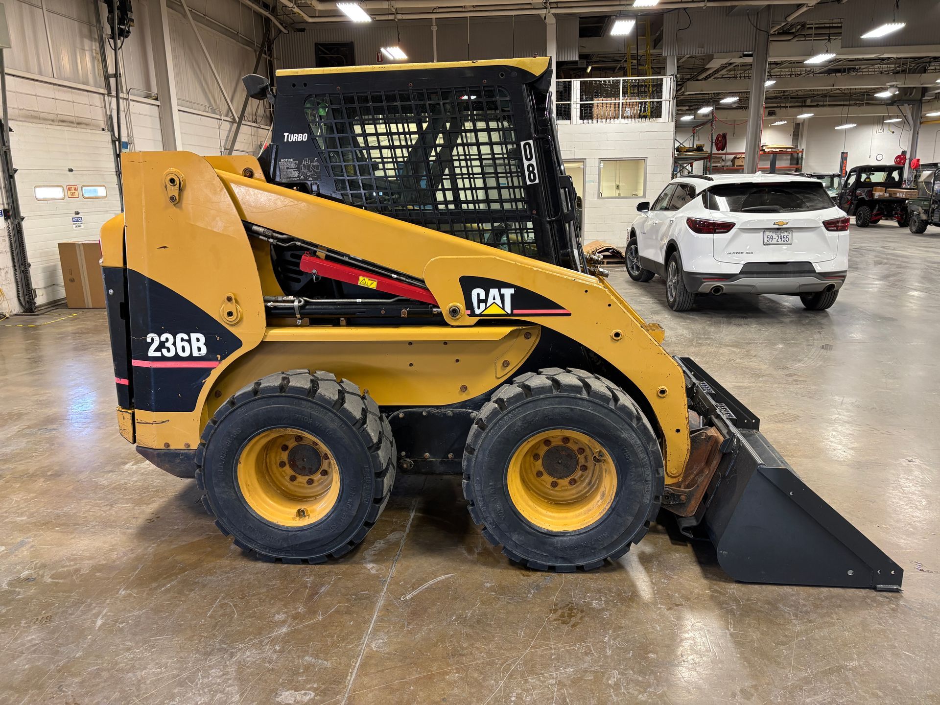Yellow Caterpillar 236B skid steer loader with bucket indoors.