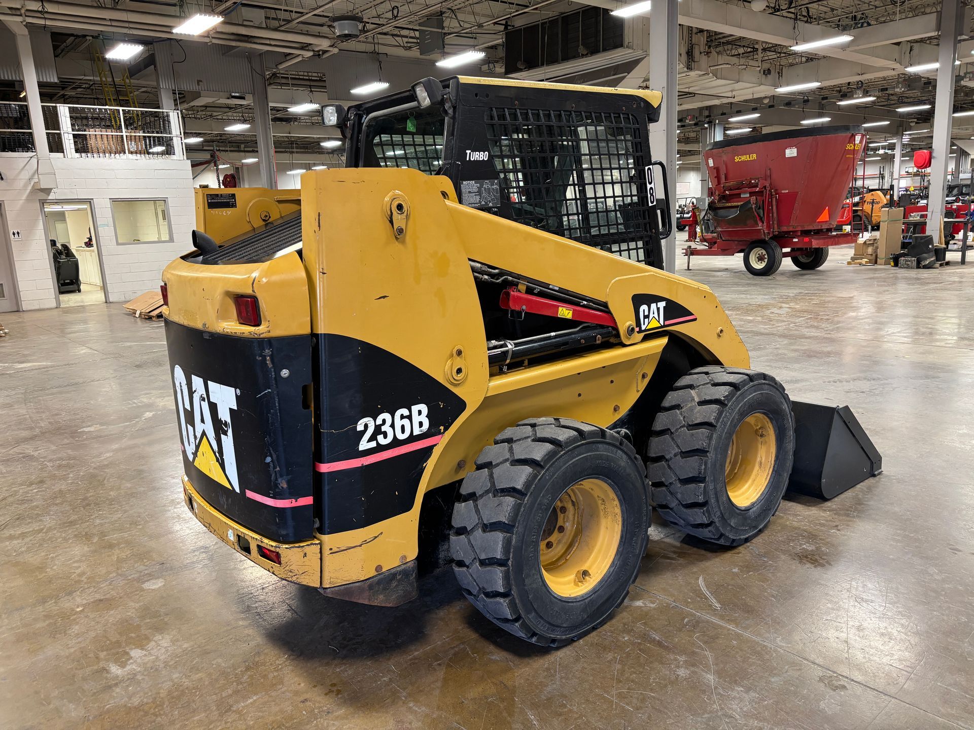 Yellow Caterpillar 236B skid steer loader with black accents, in a warehouse.