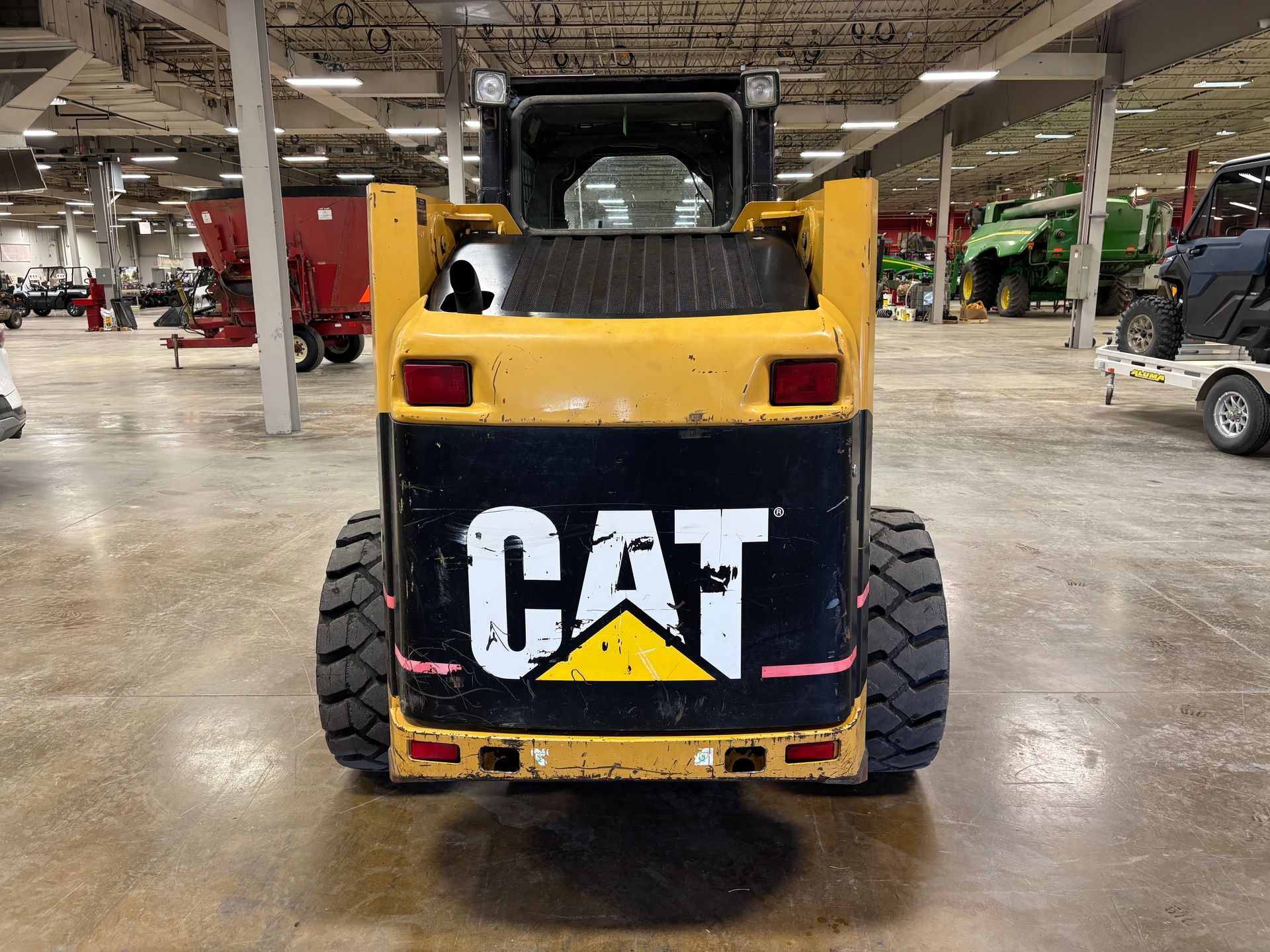 Rear view of a yellow and black Caterpillar skid steer loader with the 