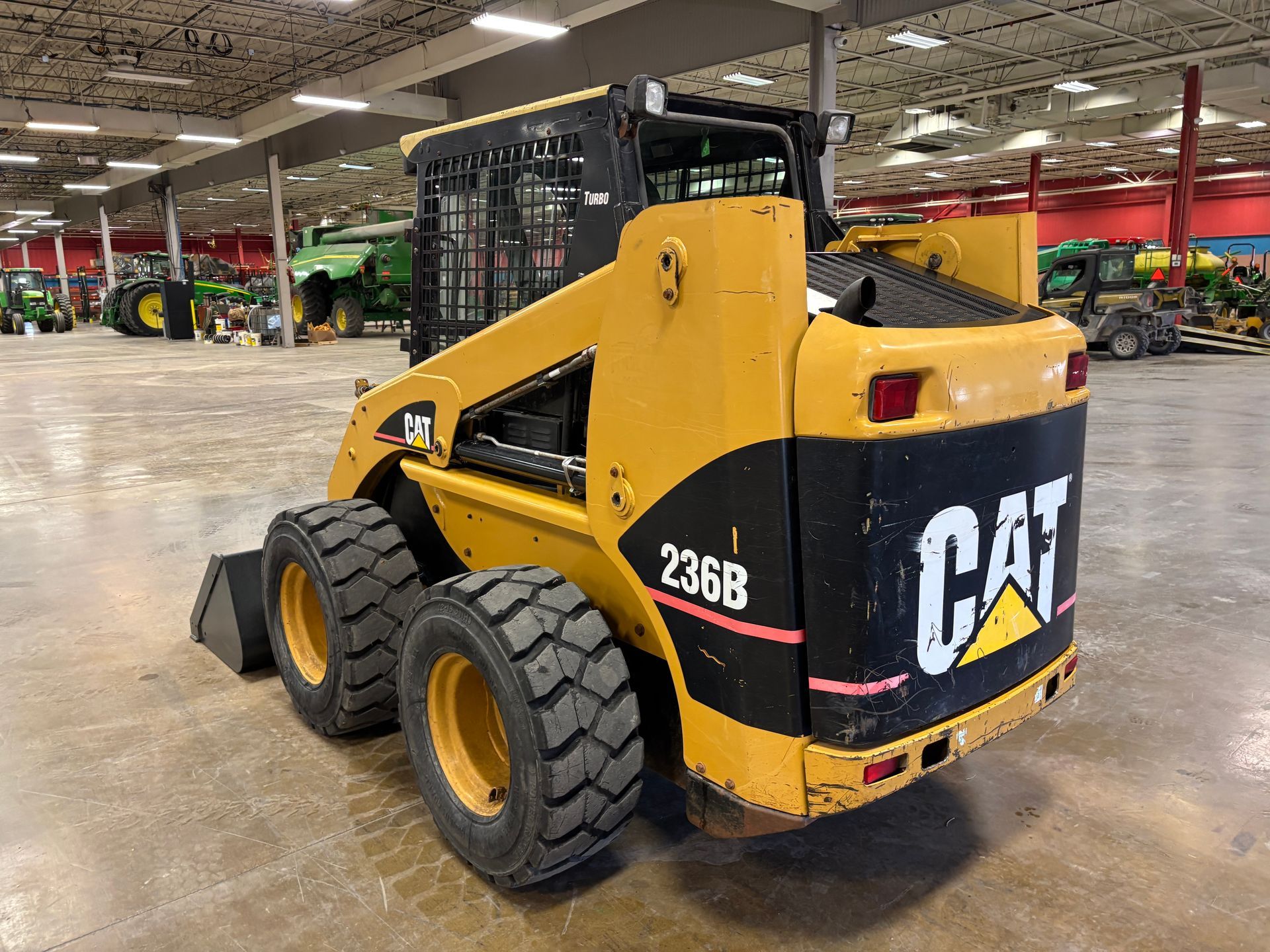 Yellow Caterpillar 236B skid steer loader in a large warehouse.