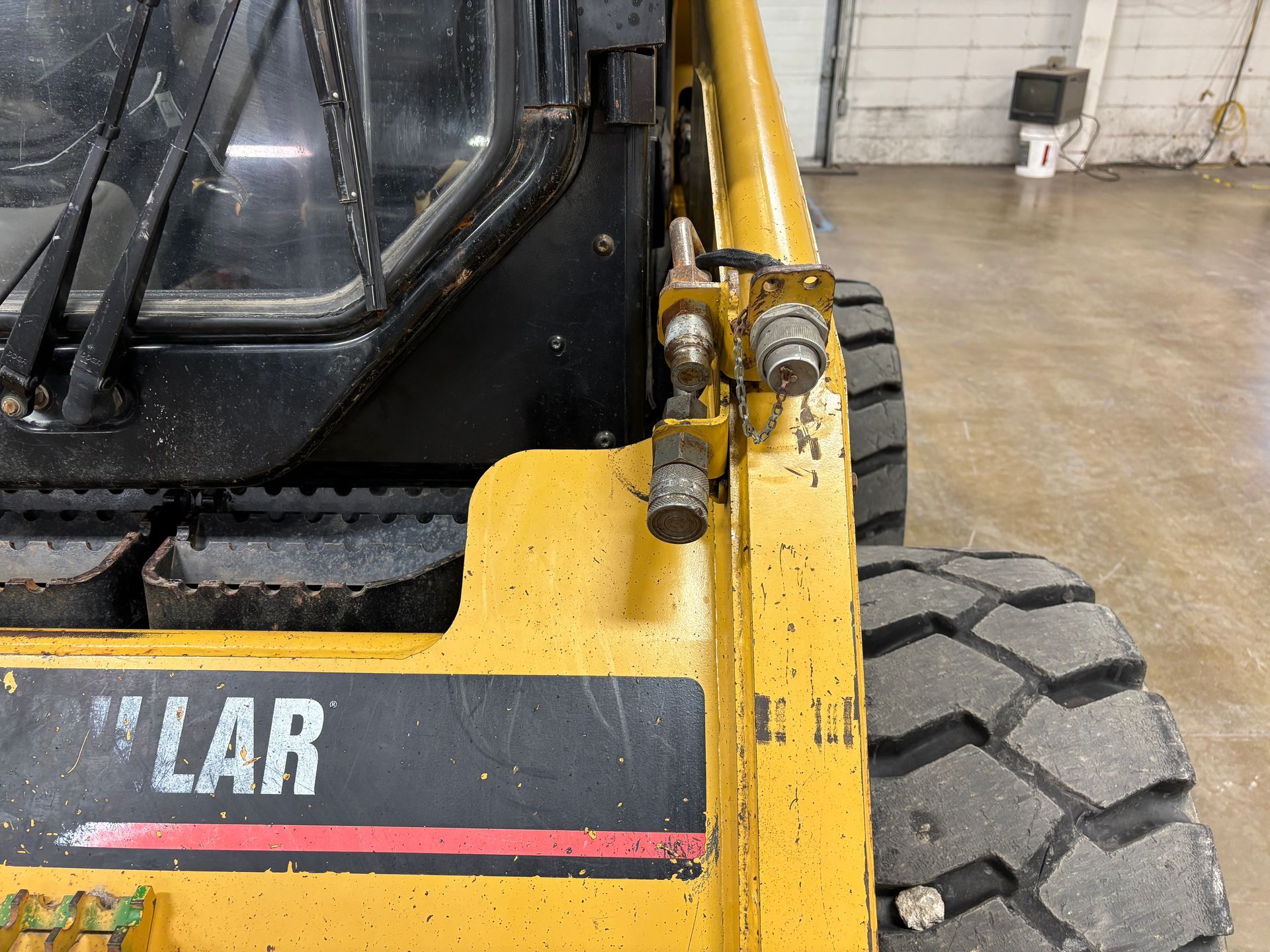 Yellow Caterpillar skid steer, showing control panel and tire.