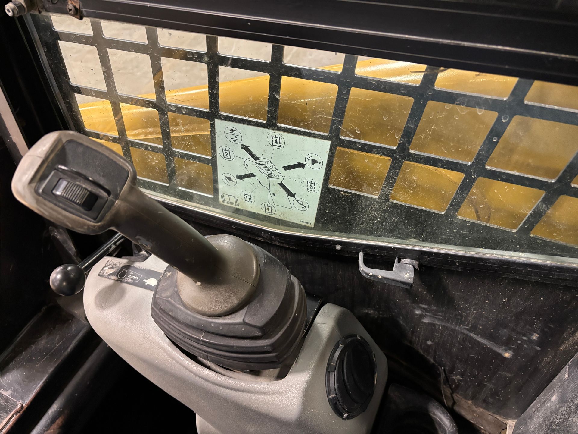 Skid steer operator control with joystick and safety screen. Interior view.