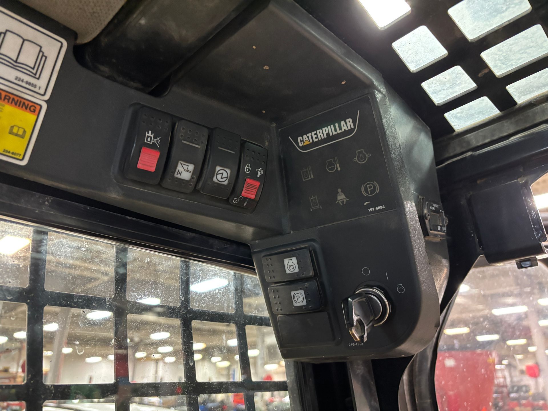 Control panel inside a Caterpillar skid steer, with multiple switches, buttons, and a key.