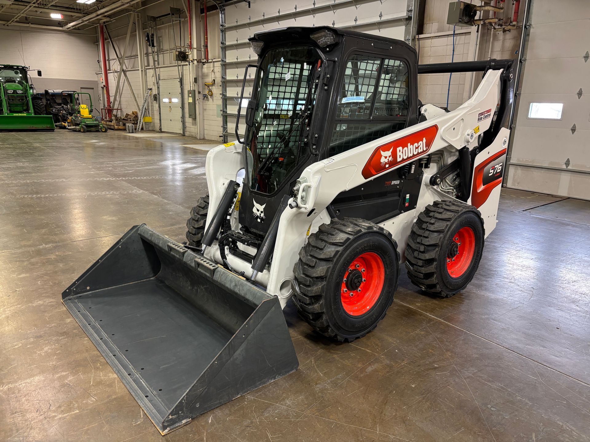 White Bobcat skid-steer loader with a black cab and bucket, red wheels.