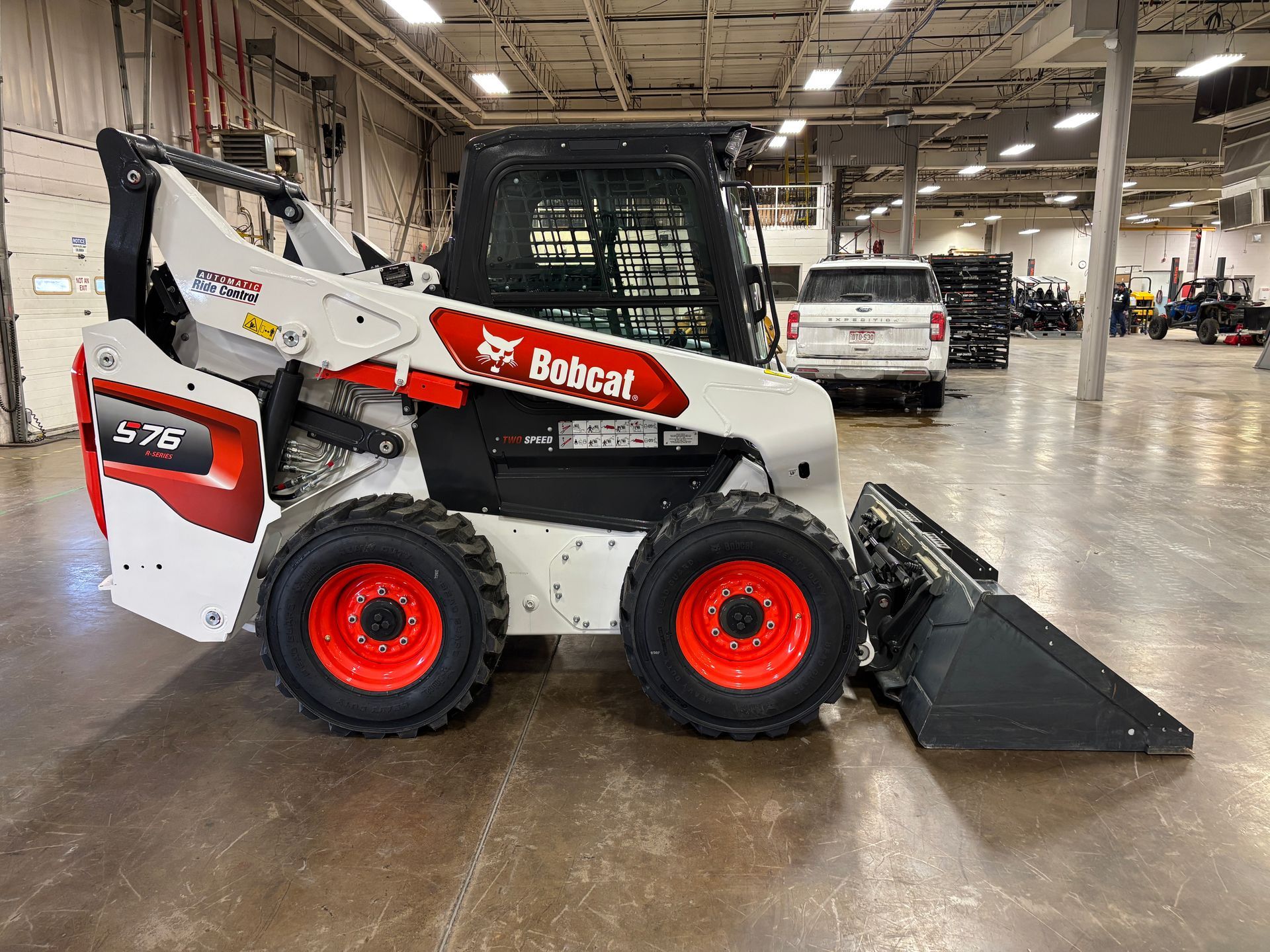 White Bobcat skid-steer loader with red accents, parked in a large indoor space.