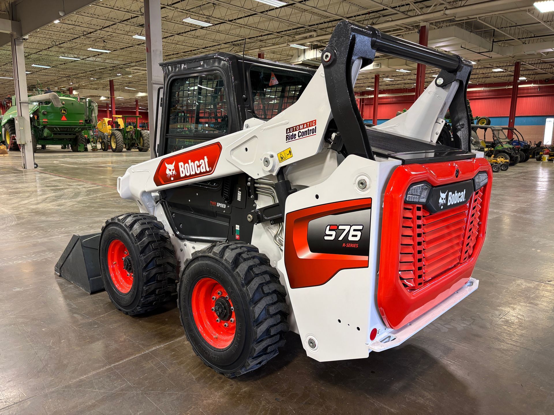 White and red Bobcat 576 skid-steer loader in a large warehouse.