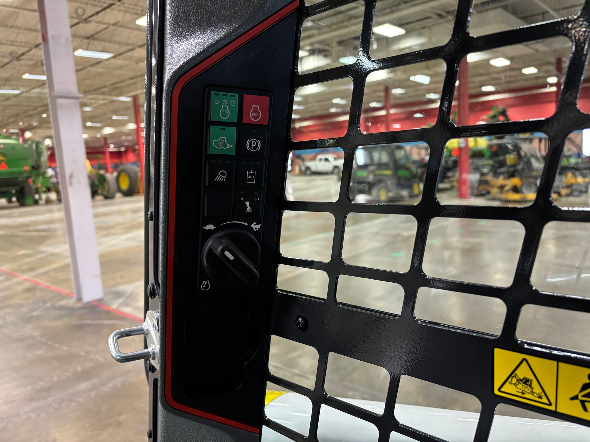 Control panel with buttons and a dial on a black machine with a safety cage.