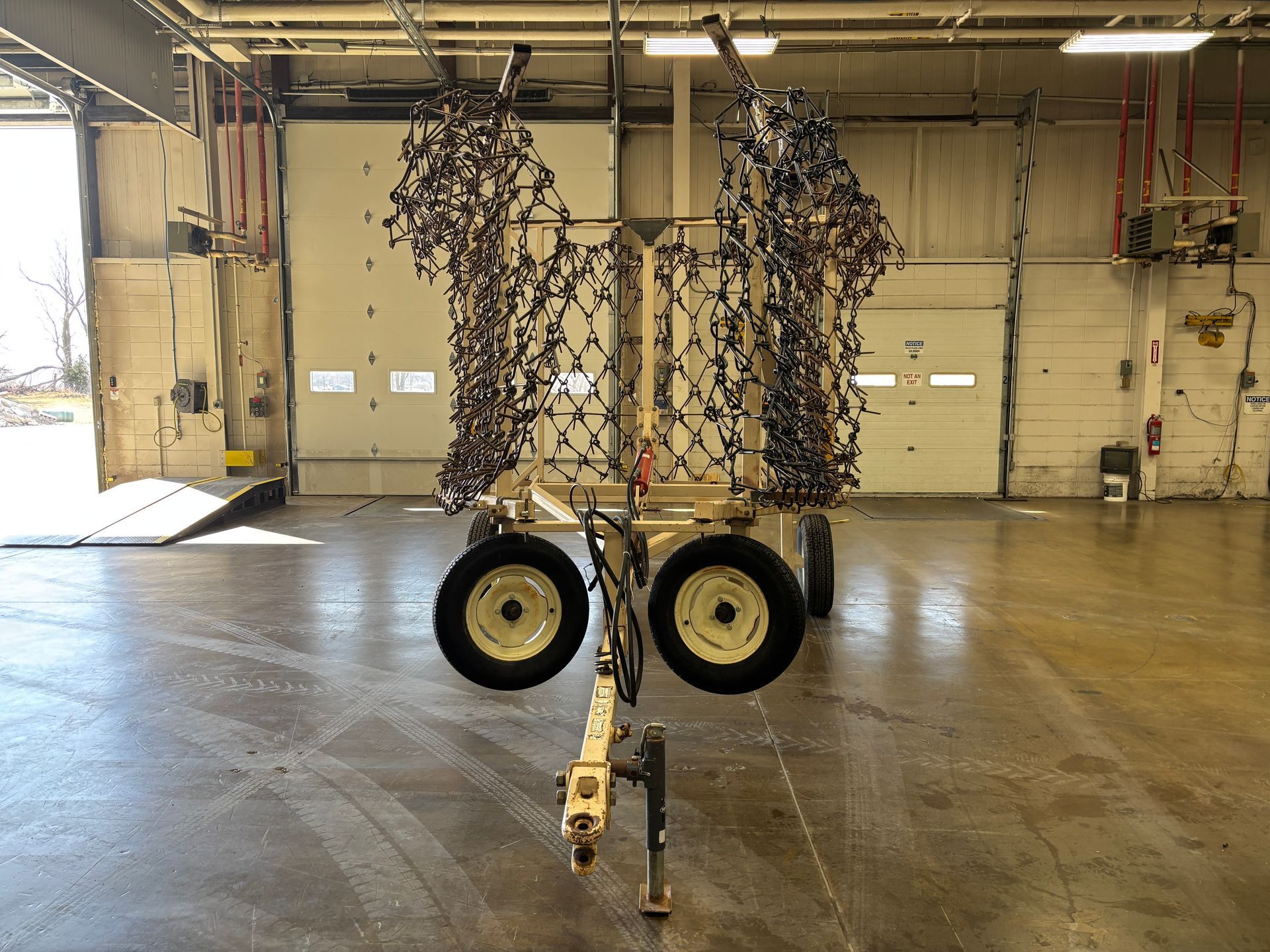A utility trailer with camouflage netting, parked inside a garage.