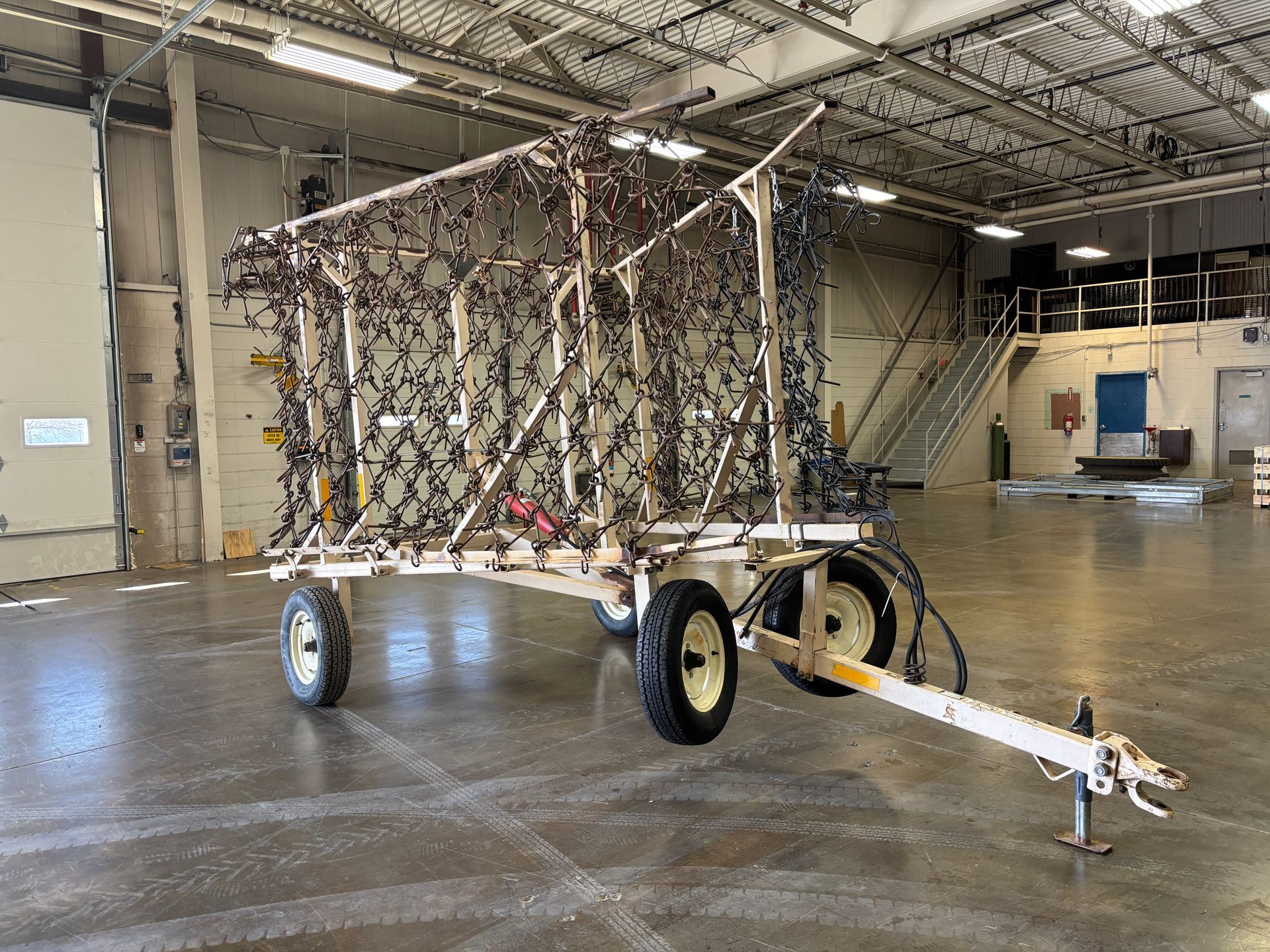 A trailer holding a complex web of wires inside a large, open warehouse.