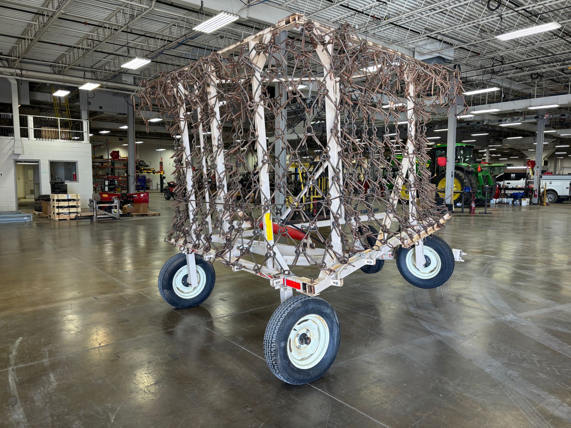 Cage-like structure on wheels, camouflaged with netting, indoors.