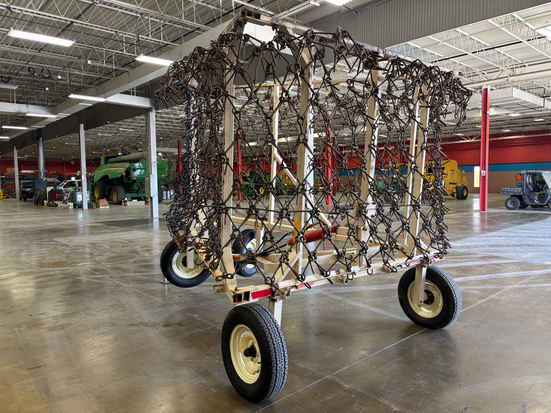 A wooden trailer with a hay net, on wheels, inside a warehouse.