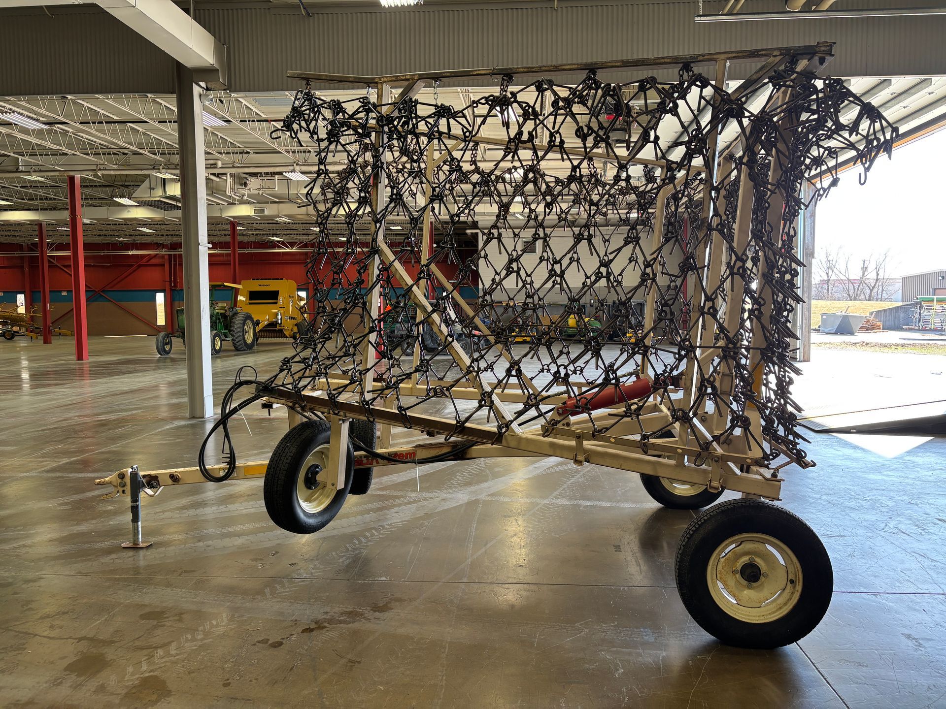 A camouflage net structure mounted on a trailer in a large indoor space.