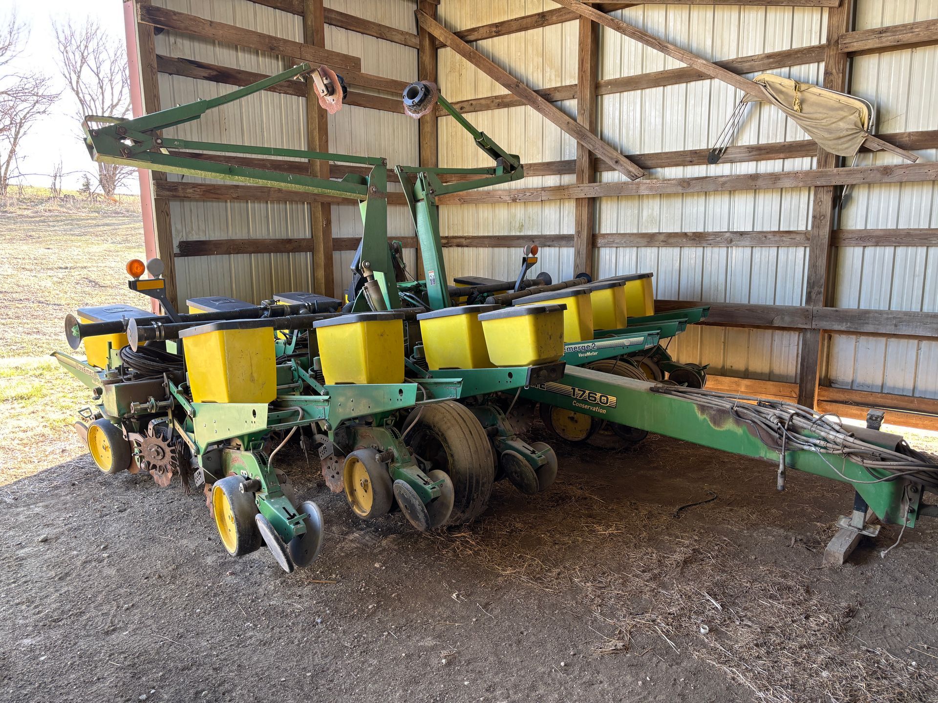Green and yellow John Deere planter in a barn, ready for use.