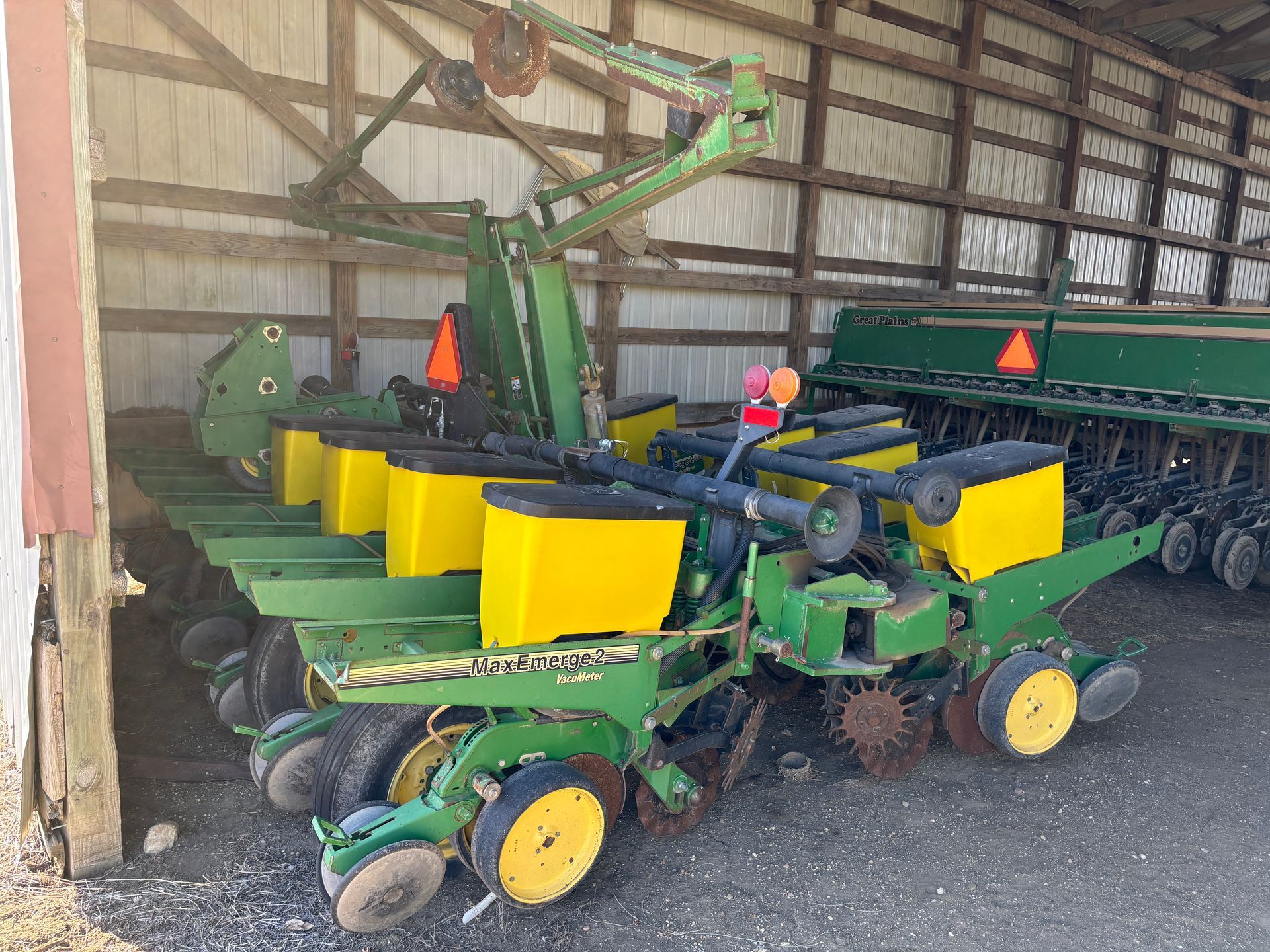 Green and yellow John Deere planter machine in a barn.