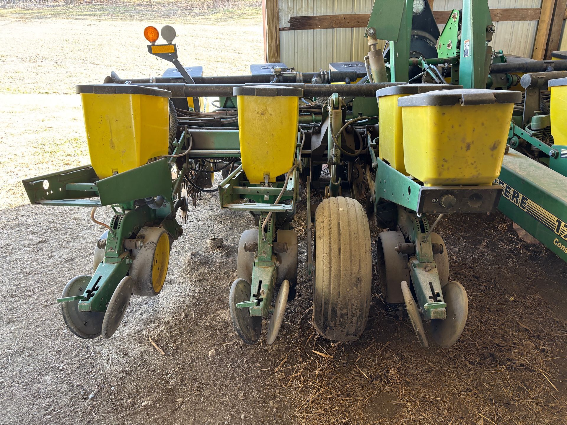 John Deere planter with three yellow seed hoppers, outdoors.