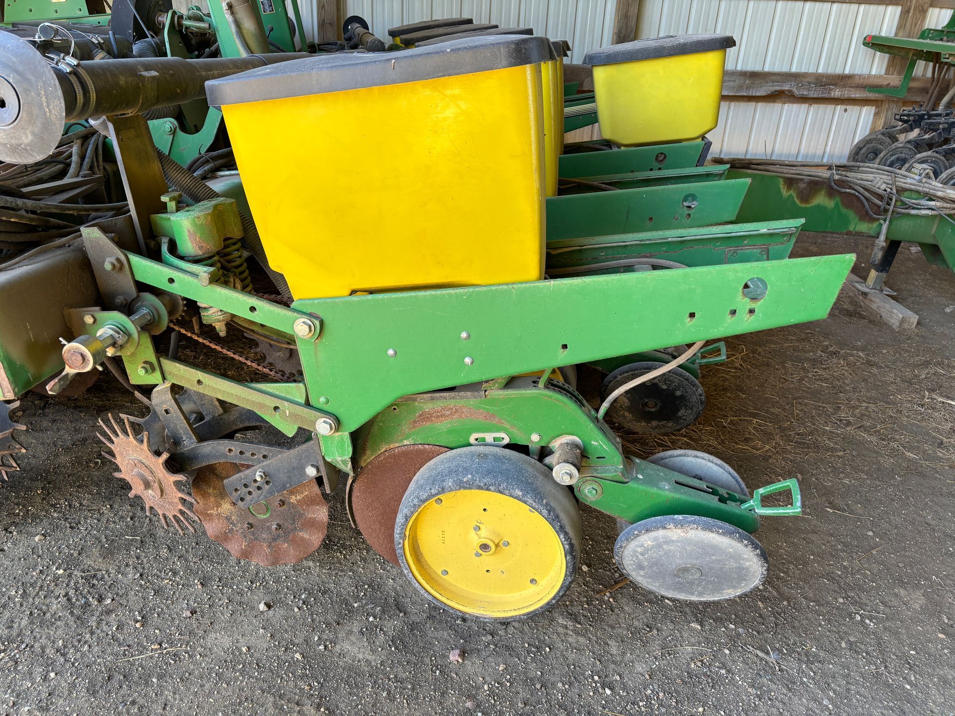 Green and yellow John Deere planter machine on a concrete surface.