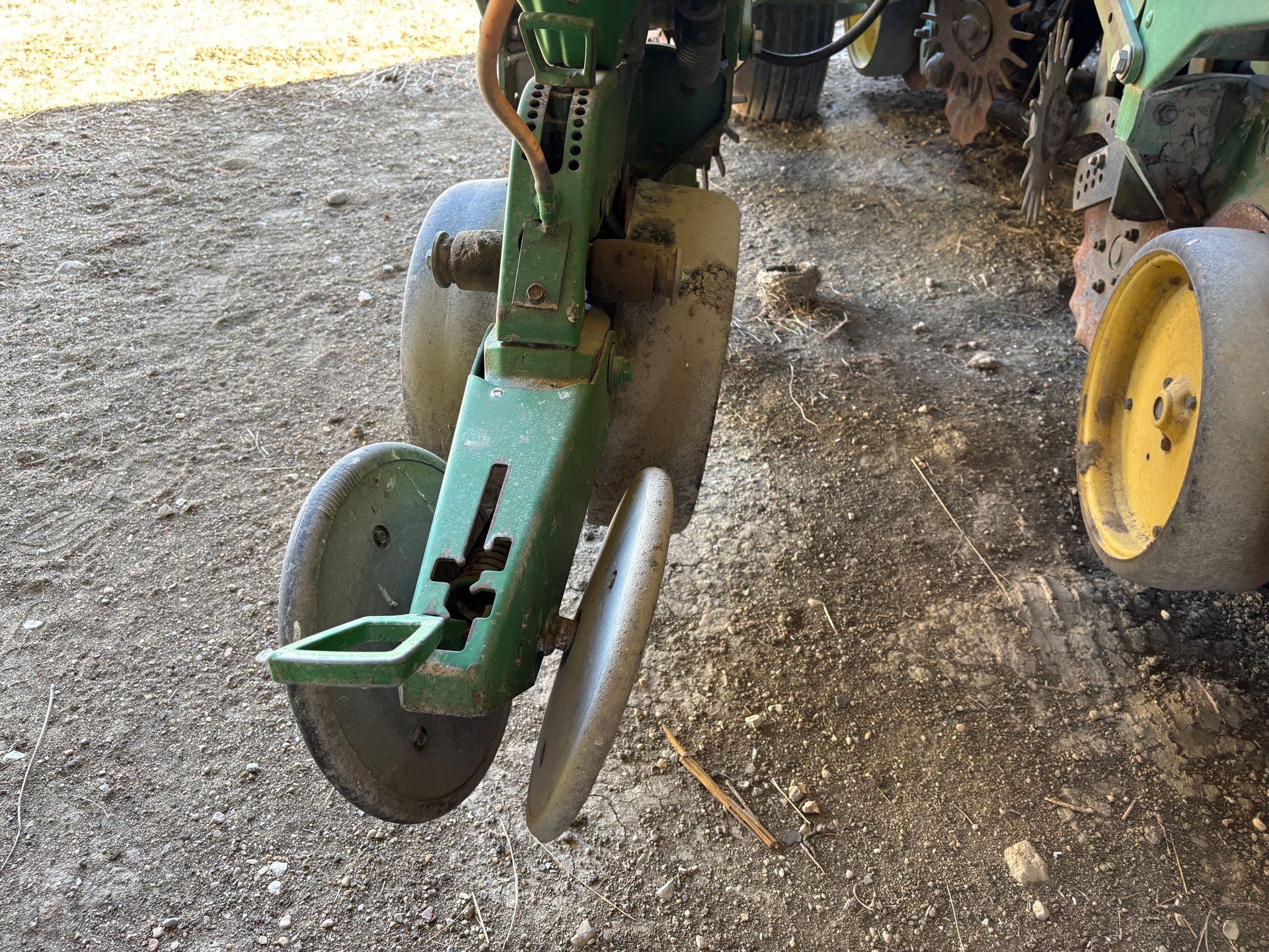 Green and yellow John Deere planter; a close-up of the disc openers and row unit.