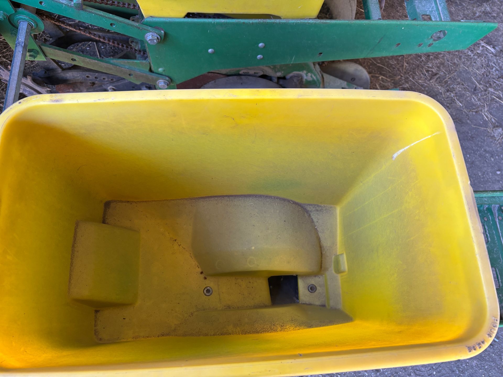 Yellow seed hopper on a green John Deere planter, viewed from above.