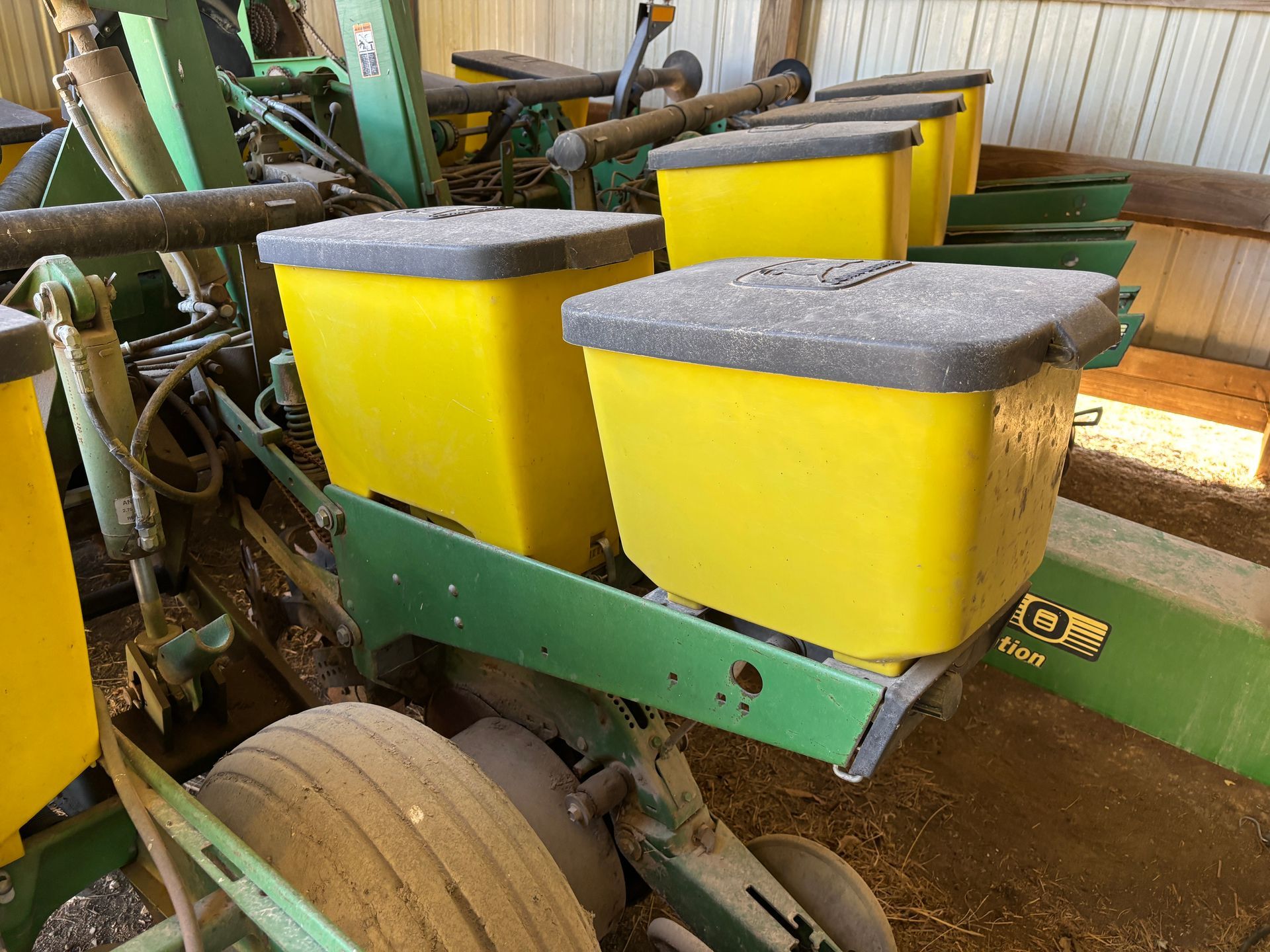 Green and yellow John Deere planter in a shed.