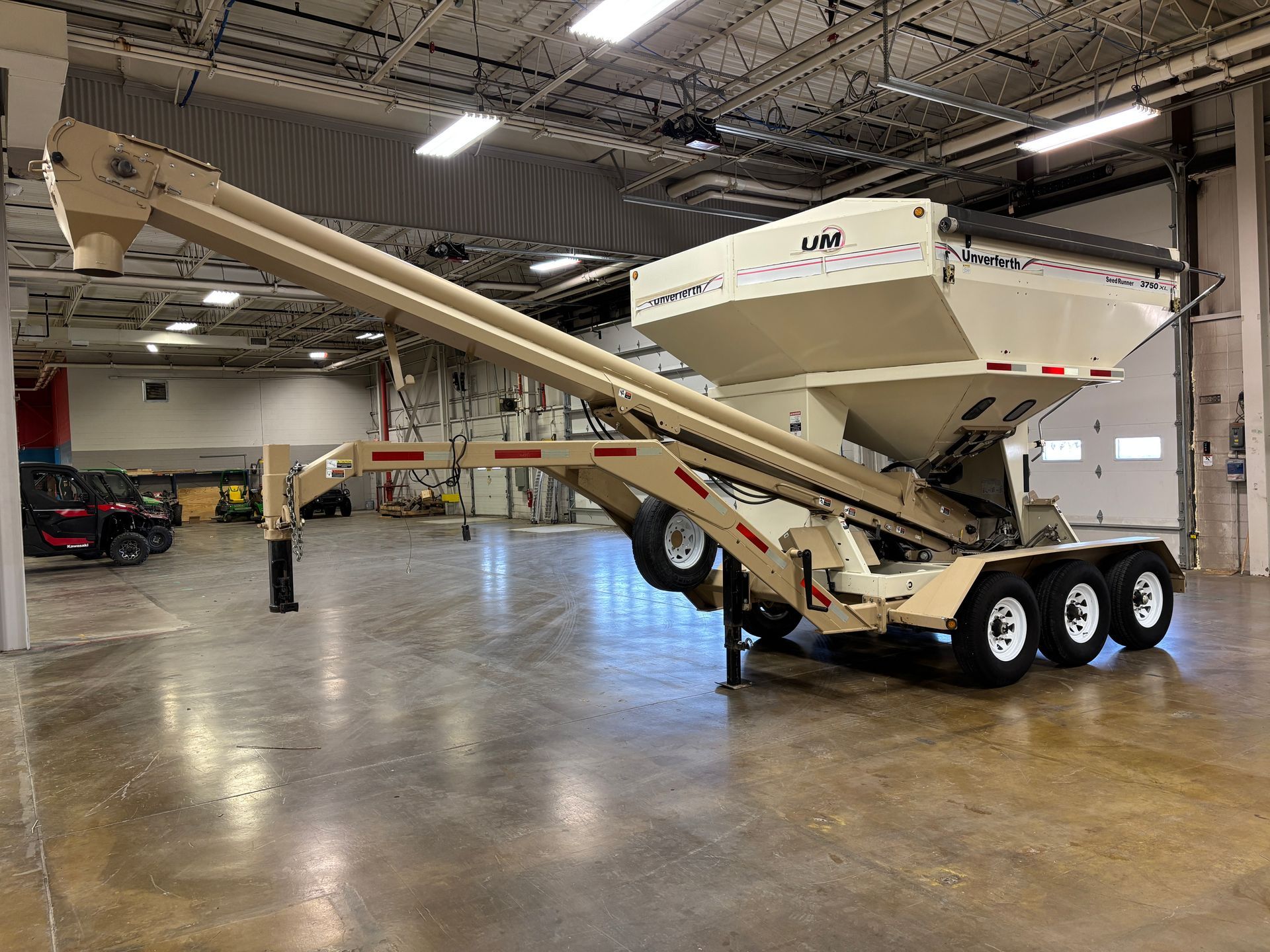Tan grain cart with auger in a warehouse.