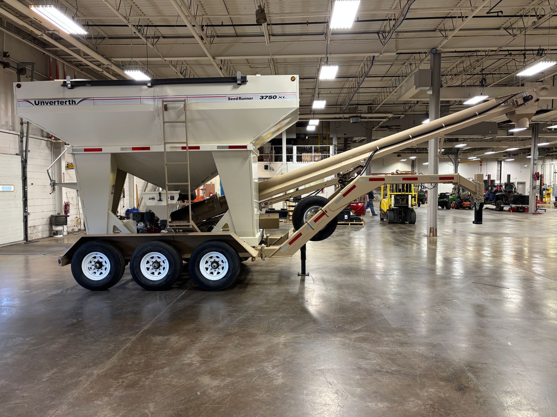 White grain cart trailer with auger in an industrial warehouse.